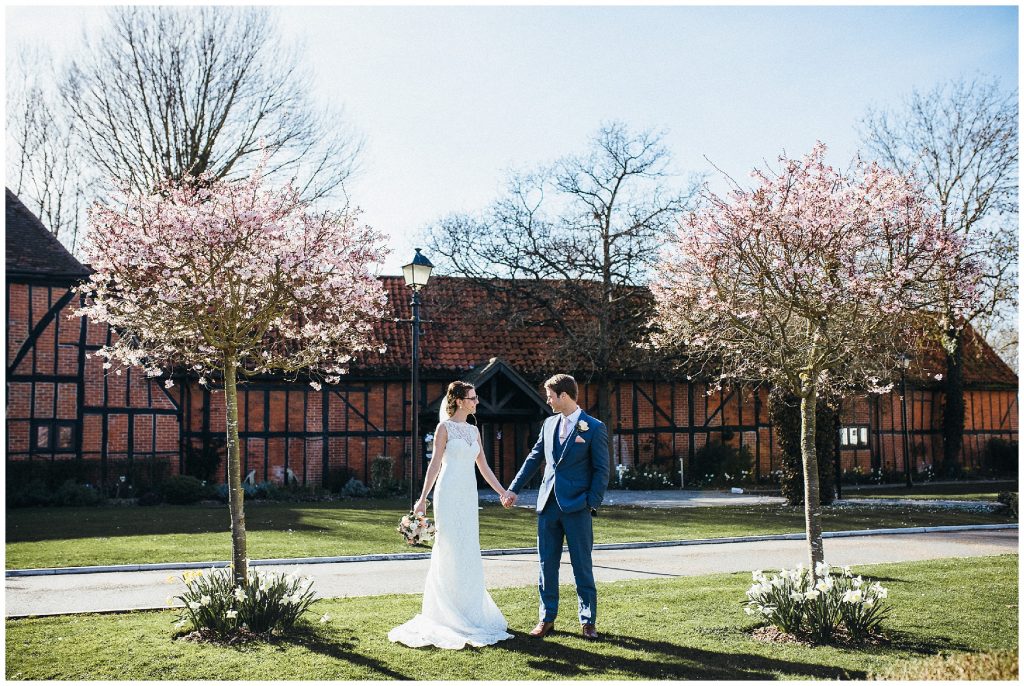 bride and groom hold hands and look at each other outside their wedding venue