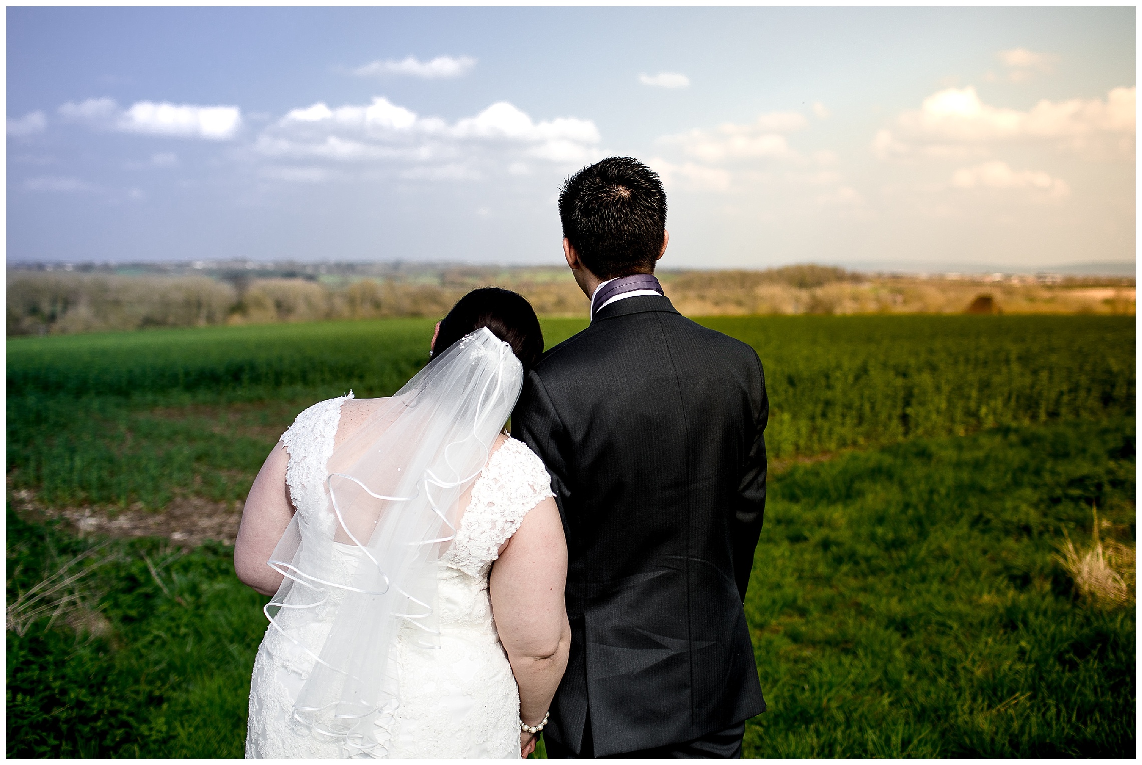 bride and groom embrace and look out onto sunset at notley tythe barn