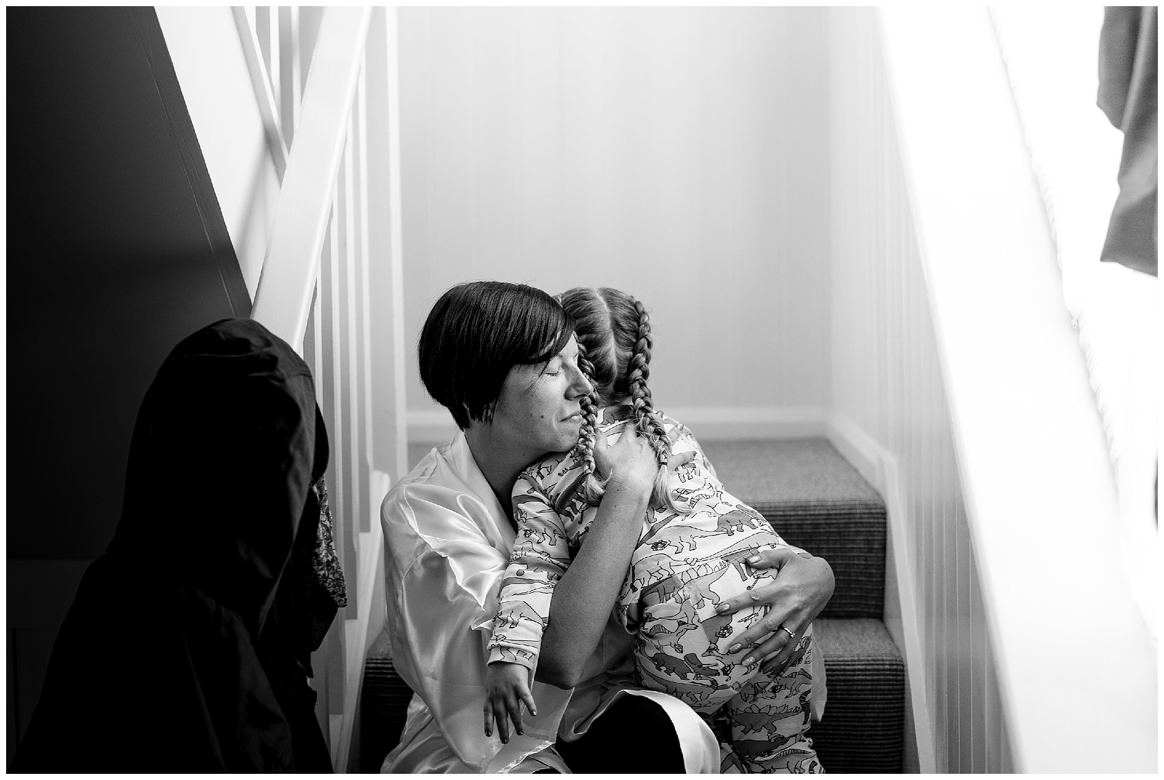 bride and the flower girl cuddle on the stairs