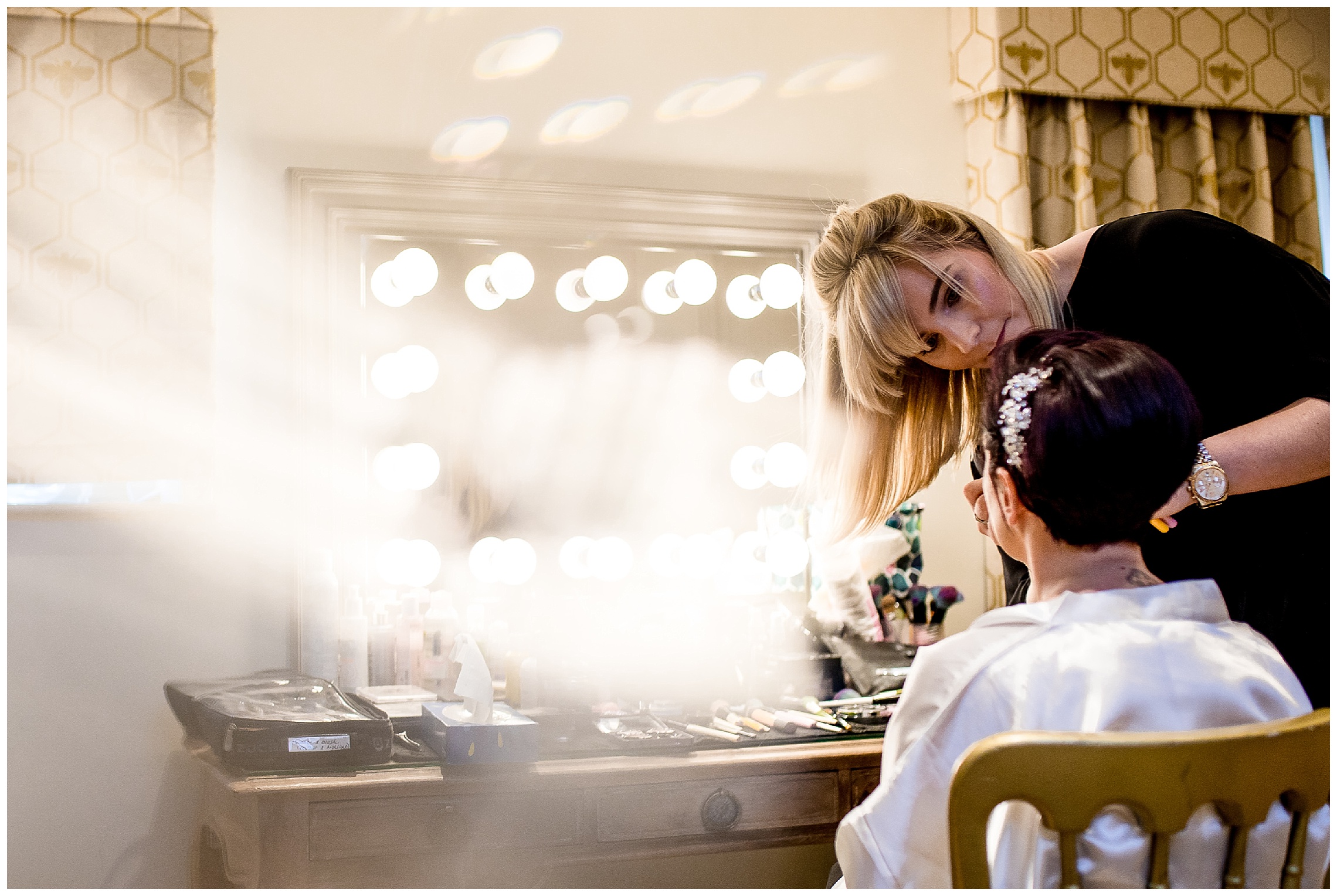 bride puts make up on in front of illuminated mirror in the bridal boudoir at south farm
