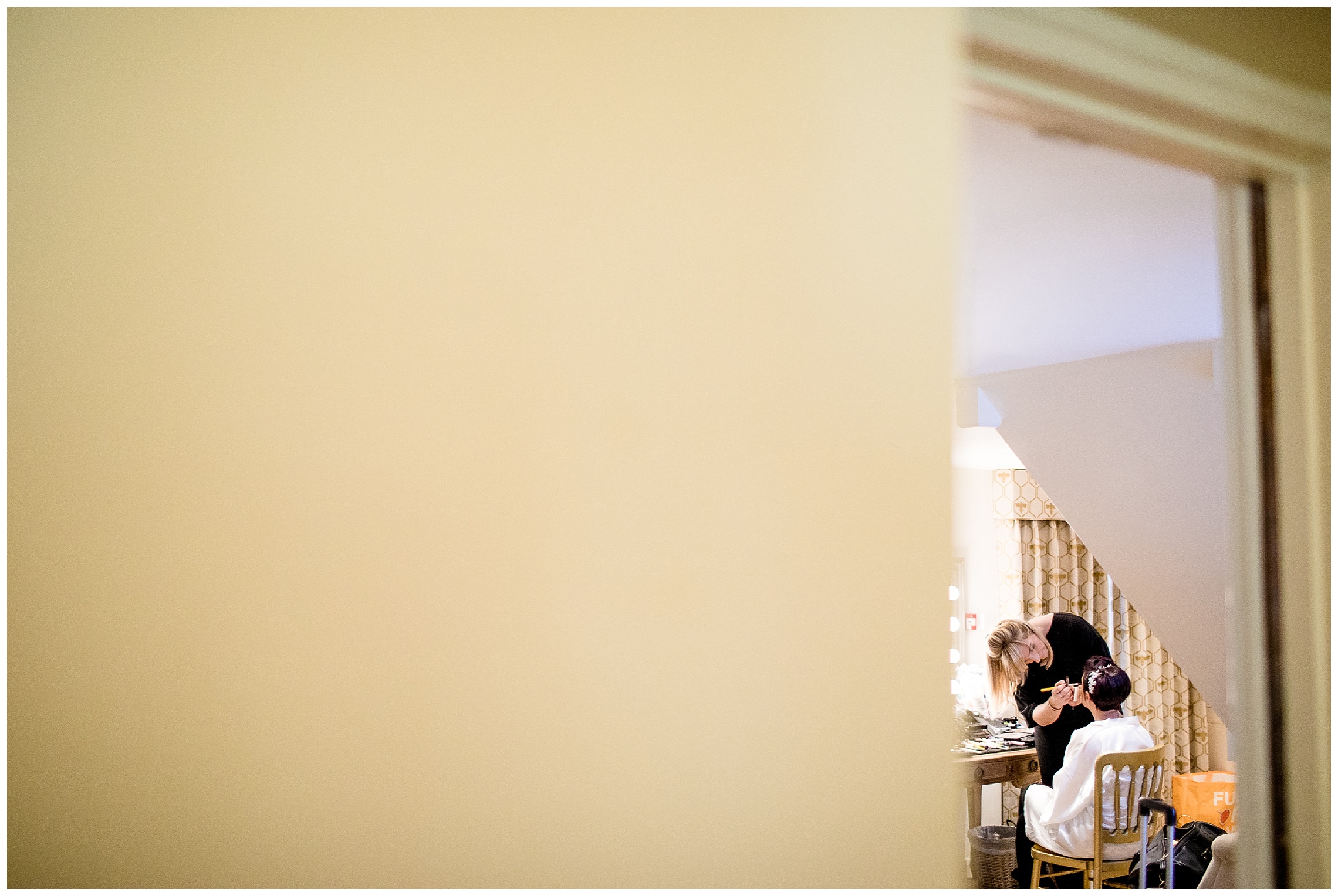 bride gets her makeup put on in the bridal boudoir