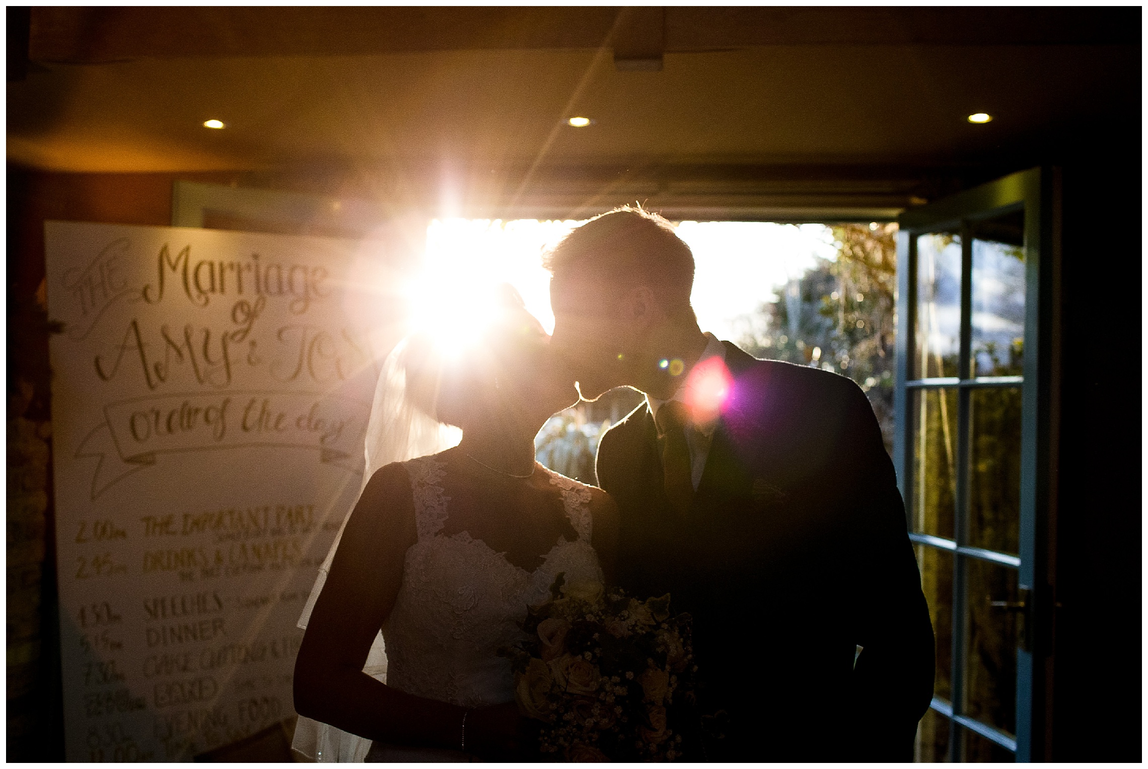 bride and groom kiss silhouette in doorway on their wedding day at south farm