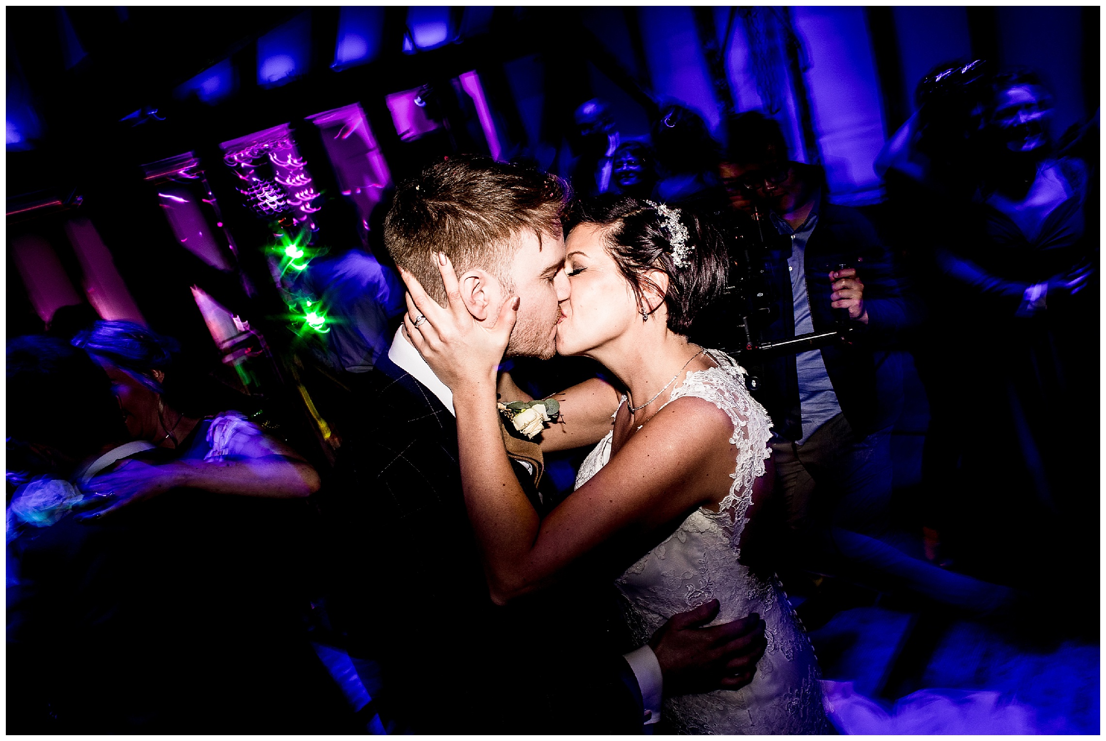 bride and groom kissing in the middle on the dance floor with lights around them at south farm
