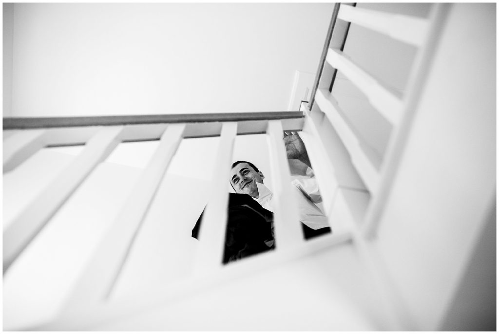 groom smiling whilst stood on stairs 