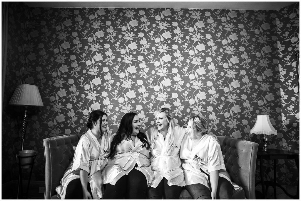 bridesmaids looking at each other and laughing whilst sitting down in bridal suite 