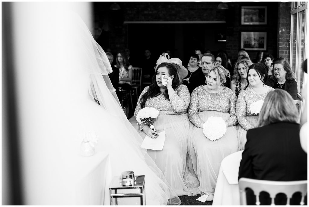 Brides sister bridesmaid wipes her tears as bride and groom say their vows 