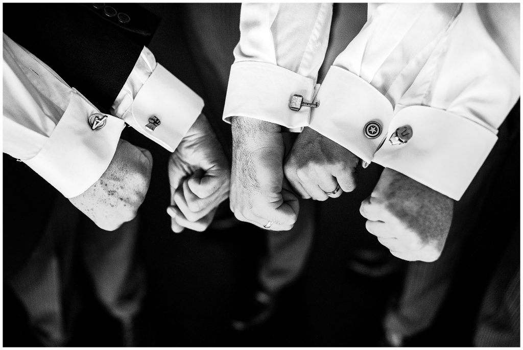 Groomsmen put their hands together to show off Marvel superhero cufflinks 