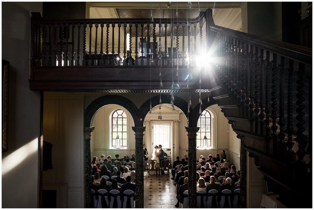 bride and groom have first kiss with light shining through window at chicheley hall