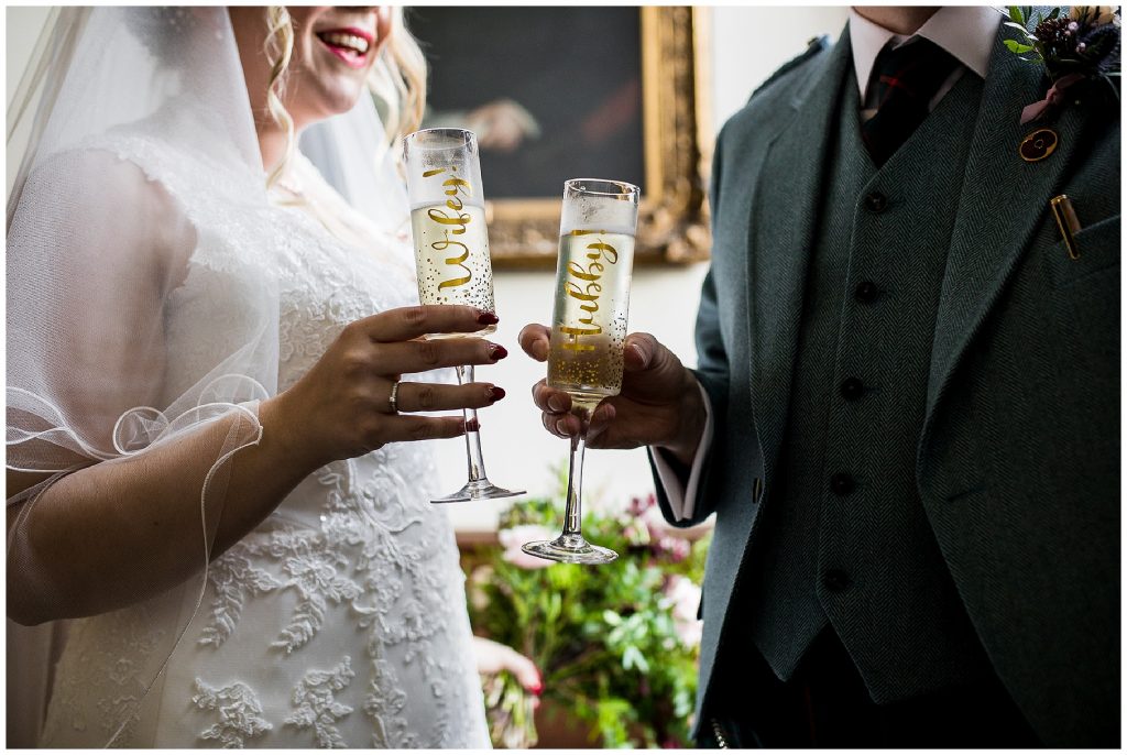 bride and groom say cheers with champagne and personalised glasses 