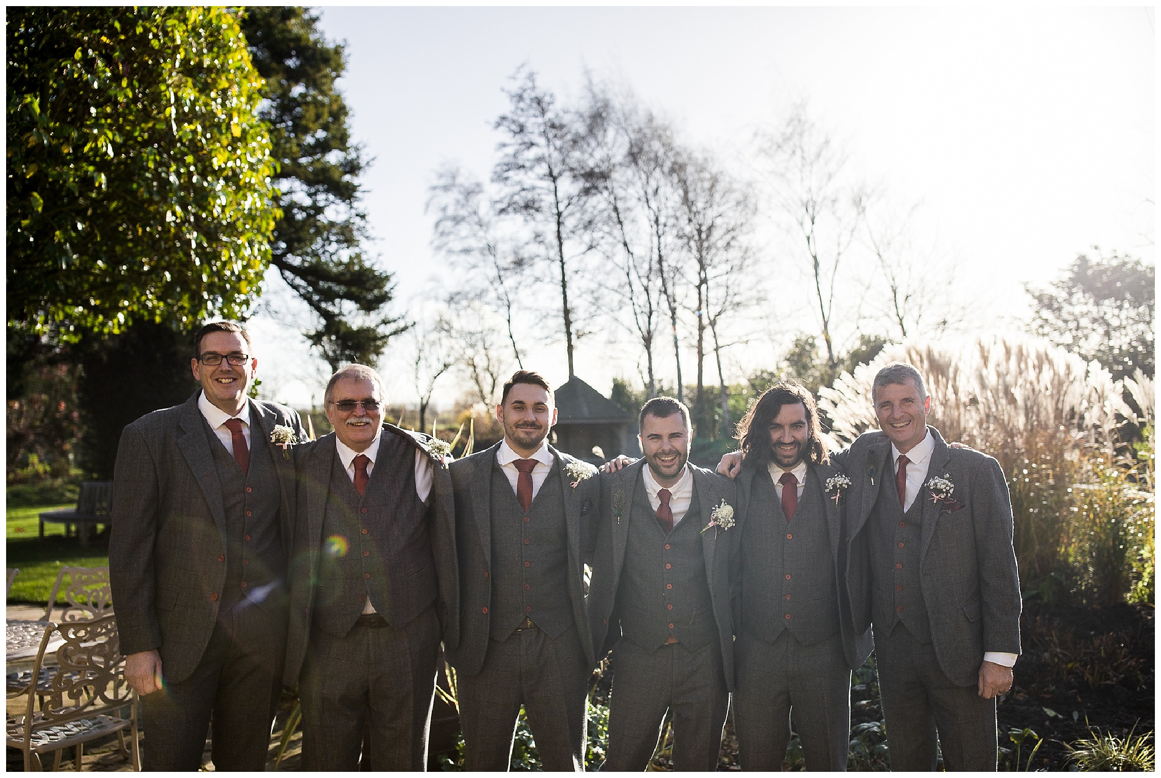 groomsmen in grey suits and red ties standing together outside