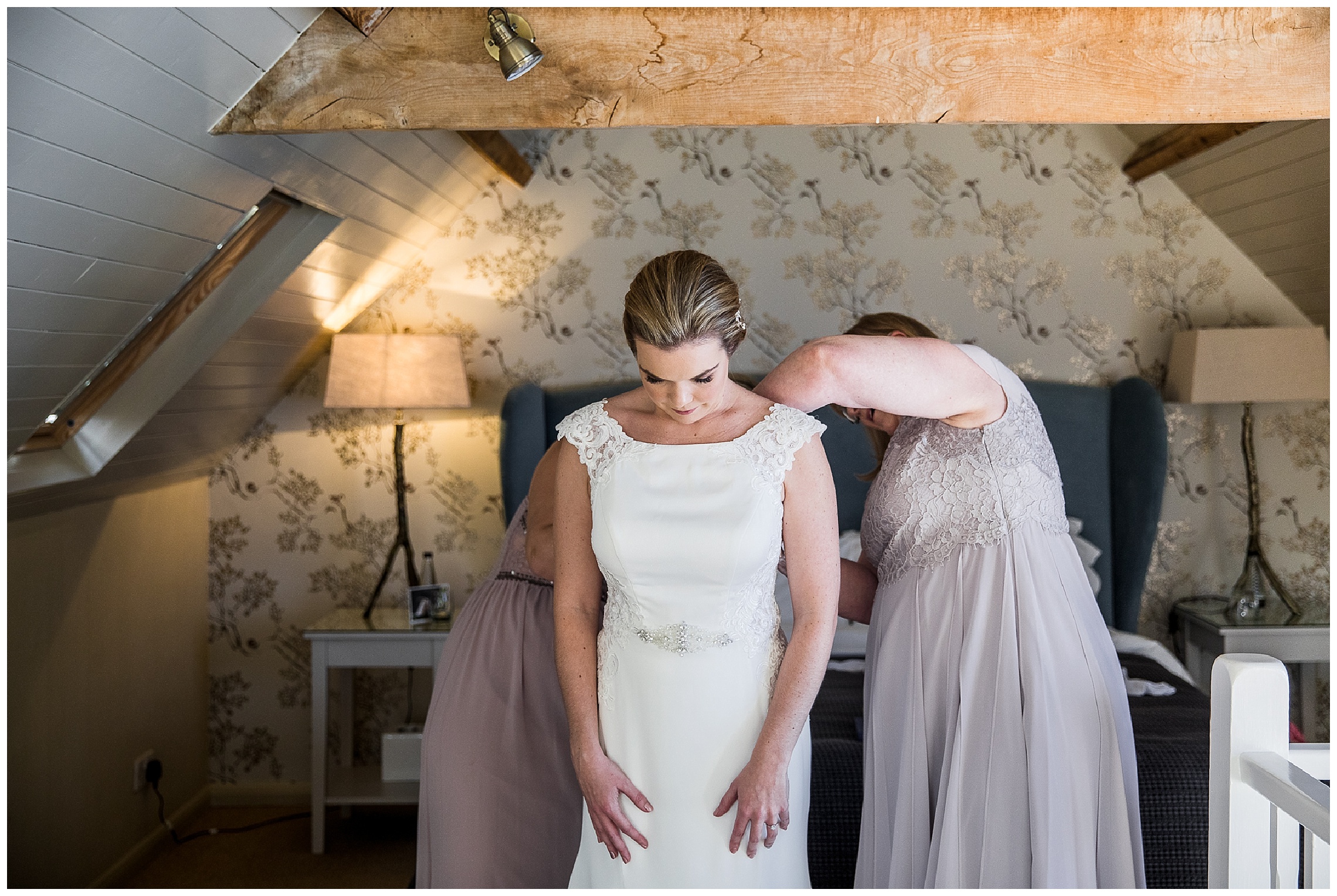 mother of bride and bridemsaid helping bride into sleek dress