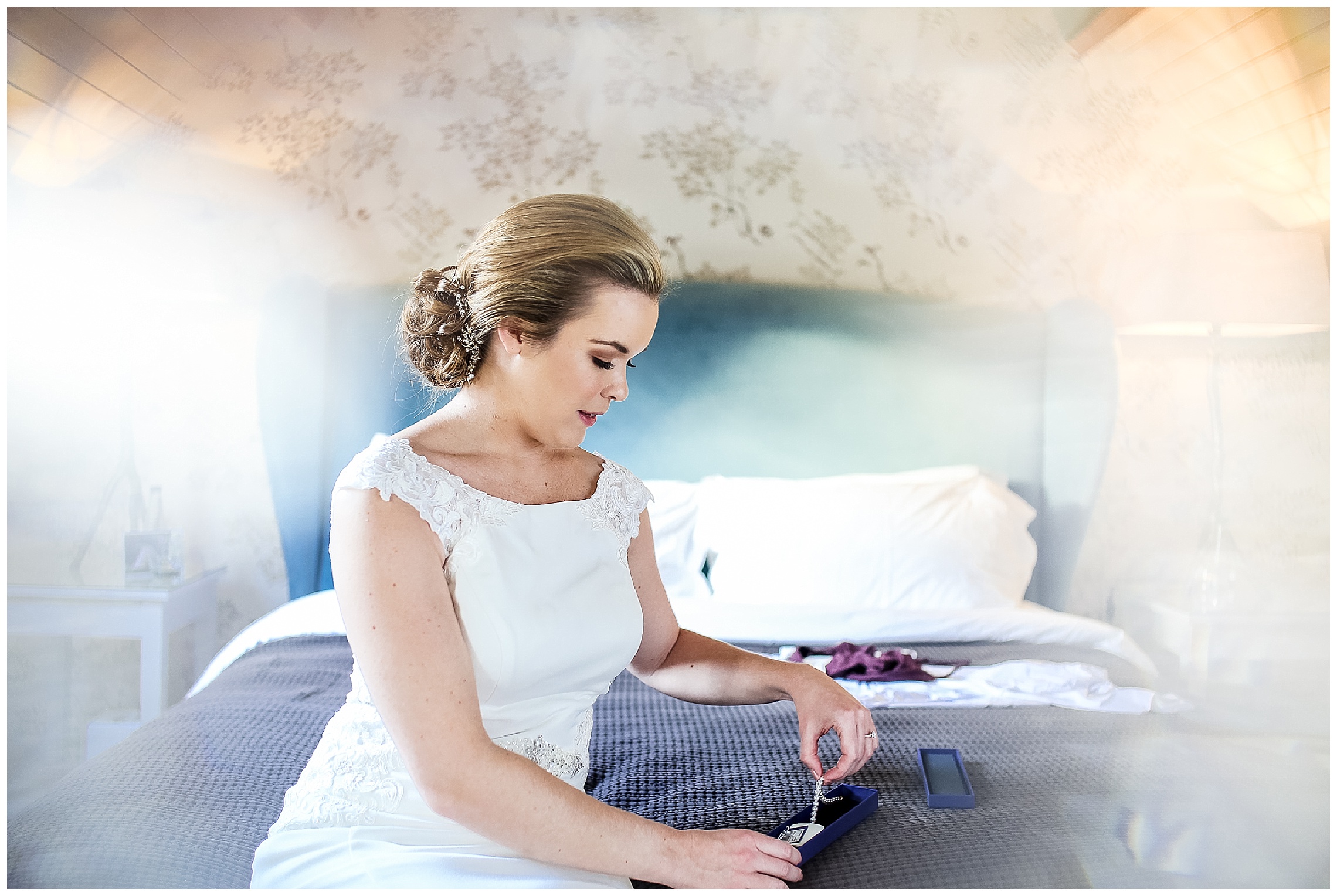 bride opening her jewellery and putting bracelet on sat on bed