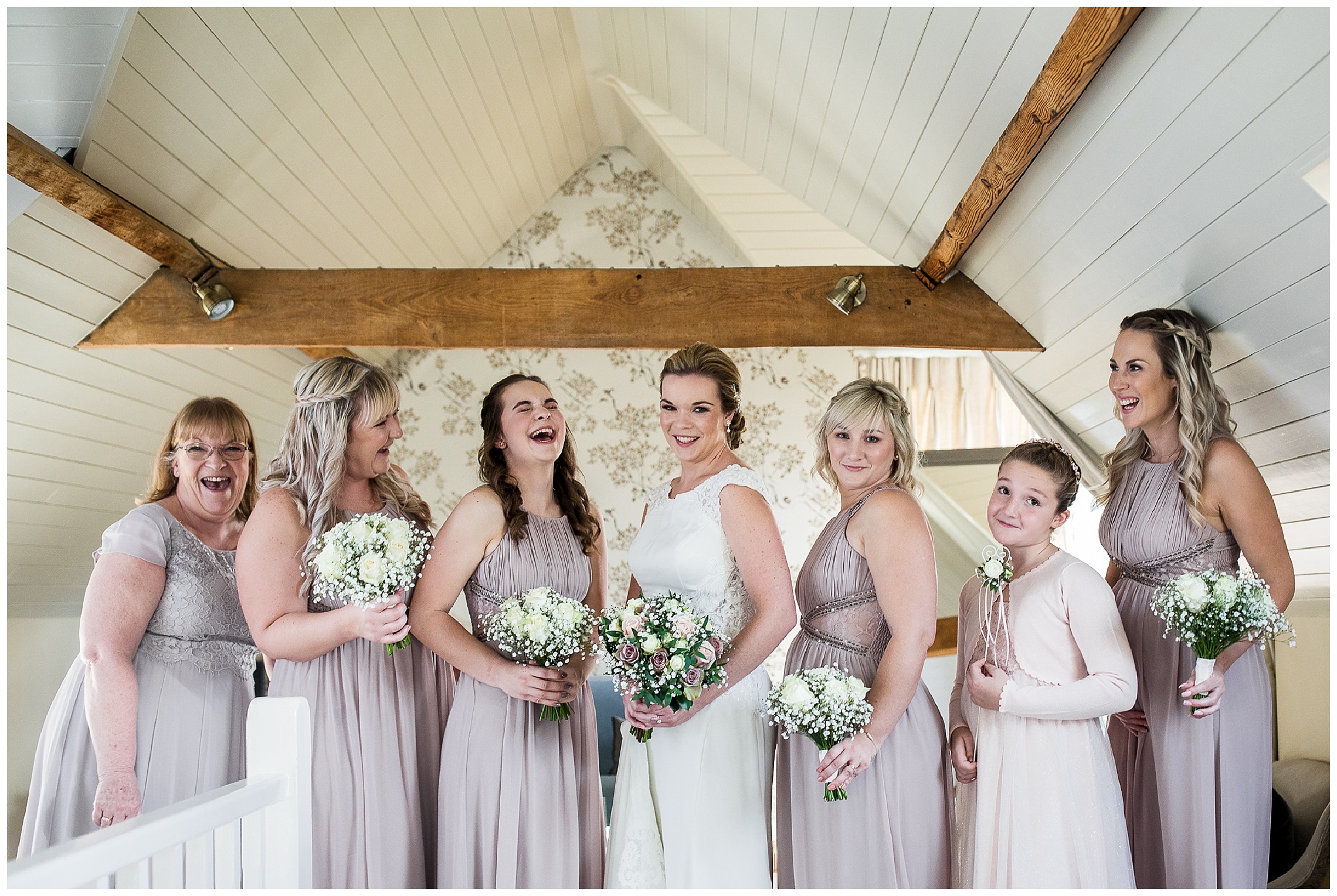 Bride and bridesmaids in lilac dresses holding flowers and smiling