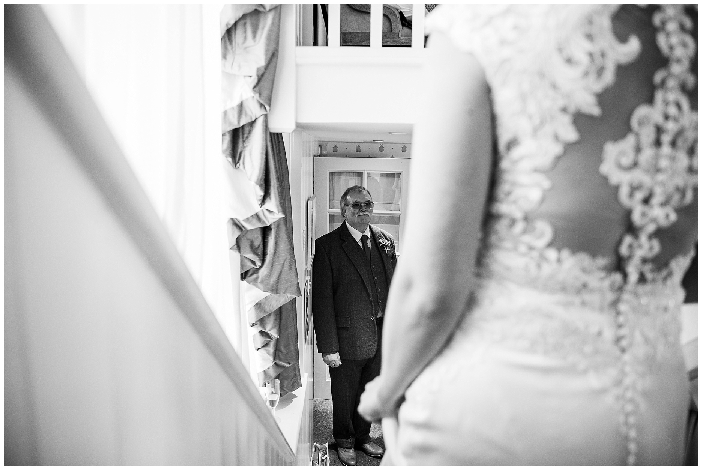 Father of the bride watches bride come down stairs towards him