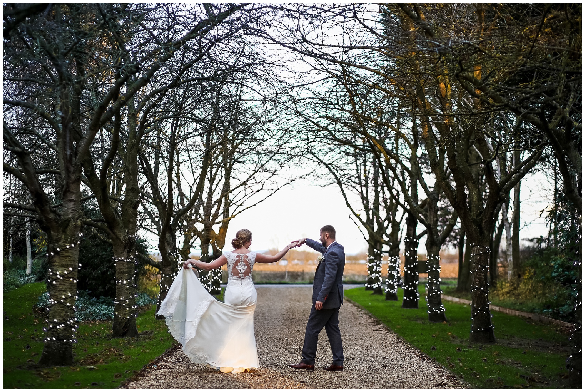 Bride and groom dance together between trees at south farm