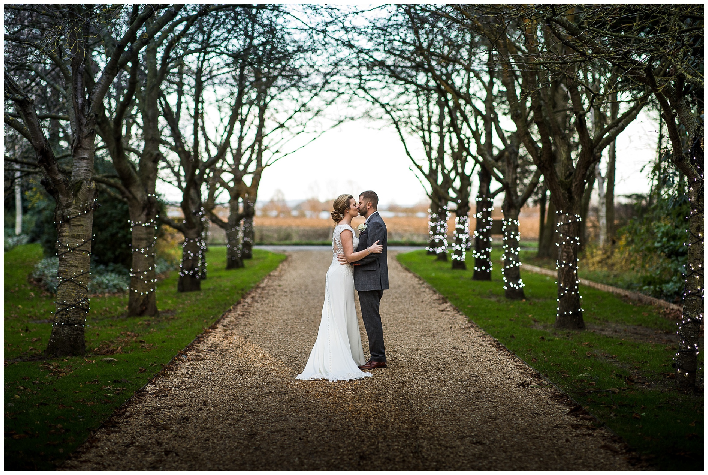 Bride and groom stand together and kiss on driveway of south farm