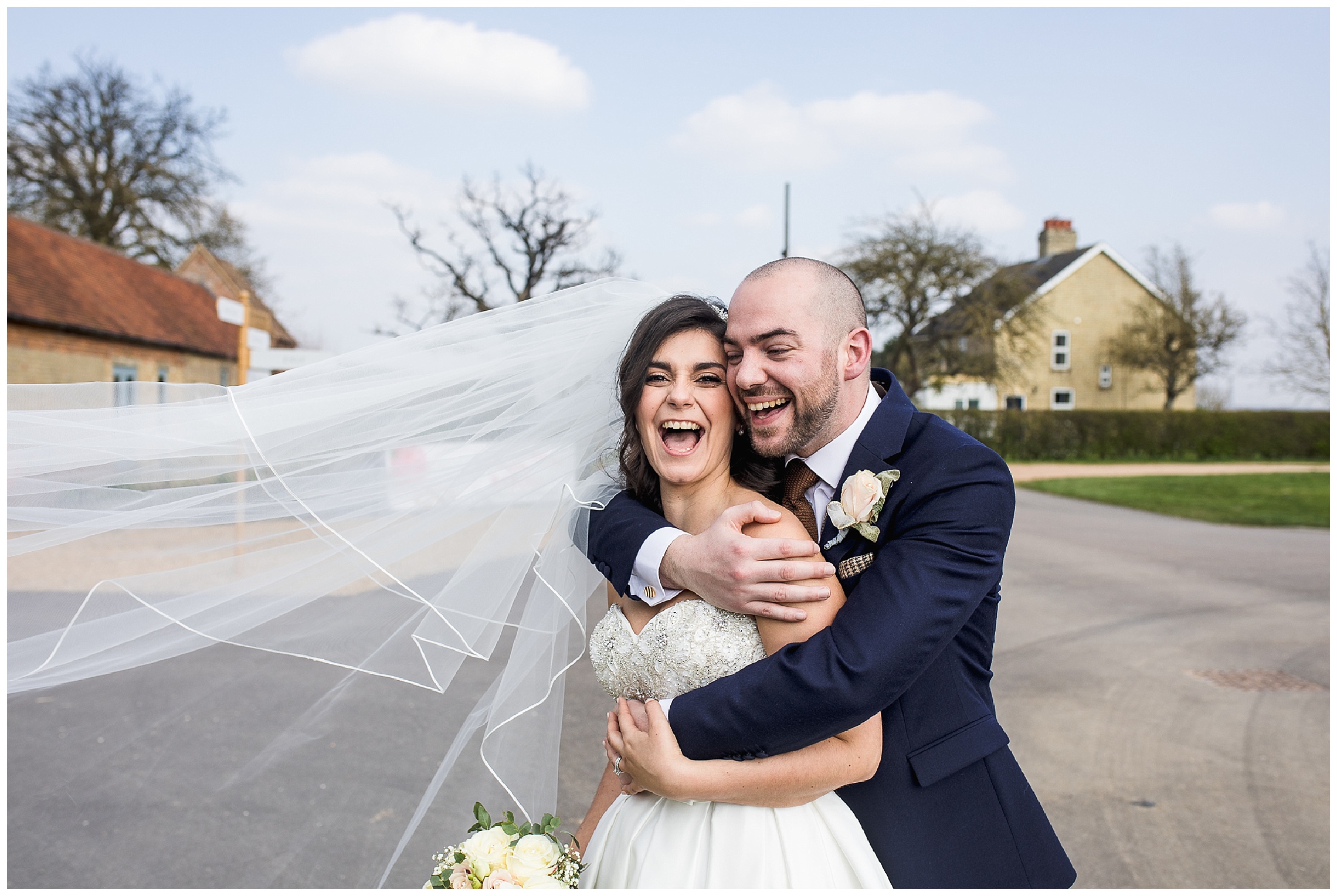 bride and groom stood together laughing as veil blows in wind at bassmead