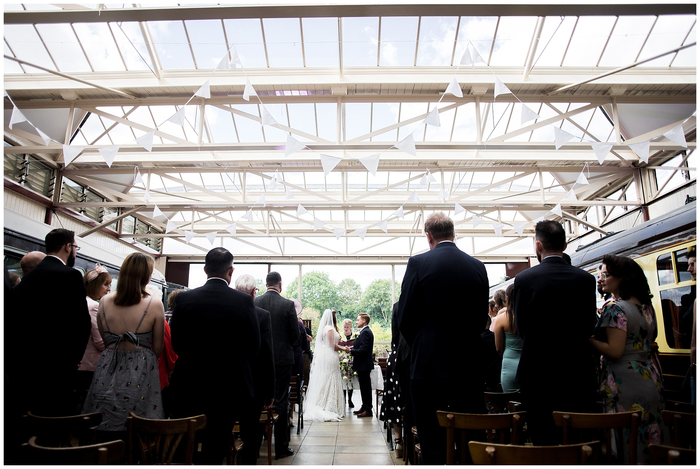 bride and groom stand in front of wedding guests getting married at bucks railway centre