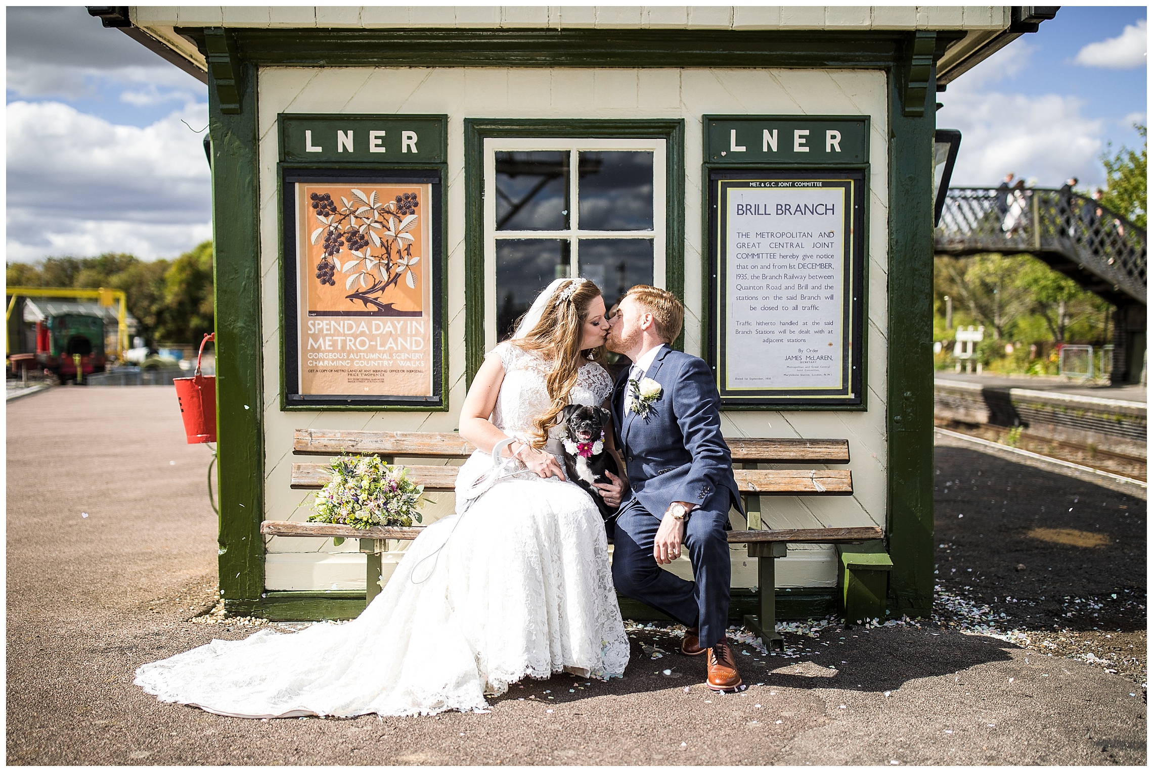 bride and groom kiss on bench as their dog sits nearby, at bucks railway centre