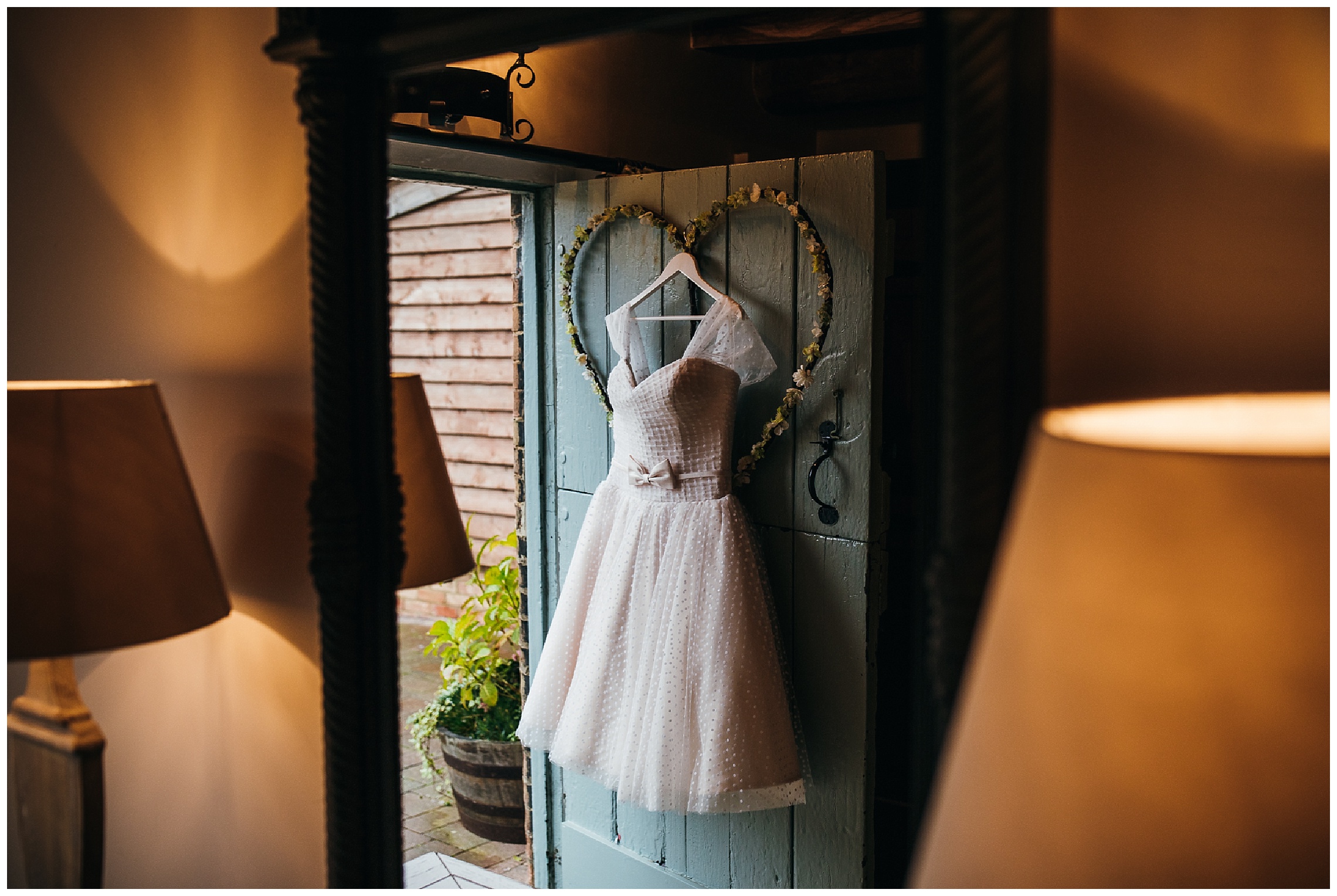 Short 50's style wedding dress with polka dots and bow hanging on blue door at bassmead manor barns