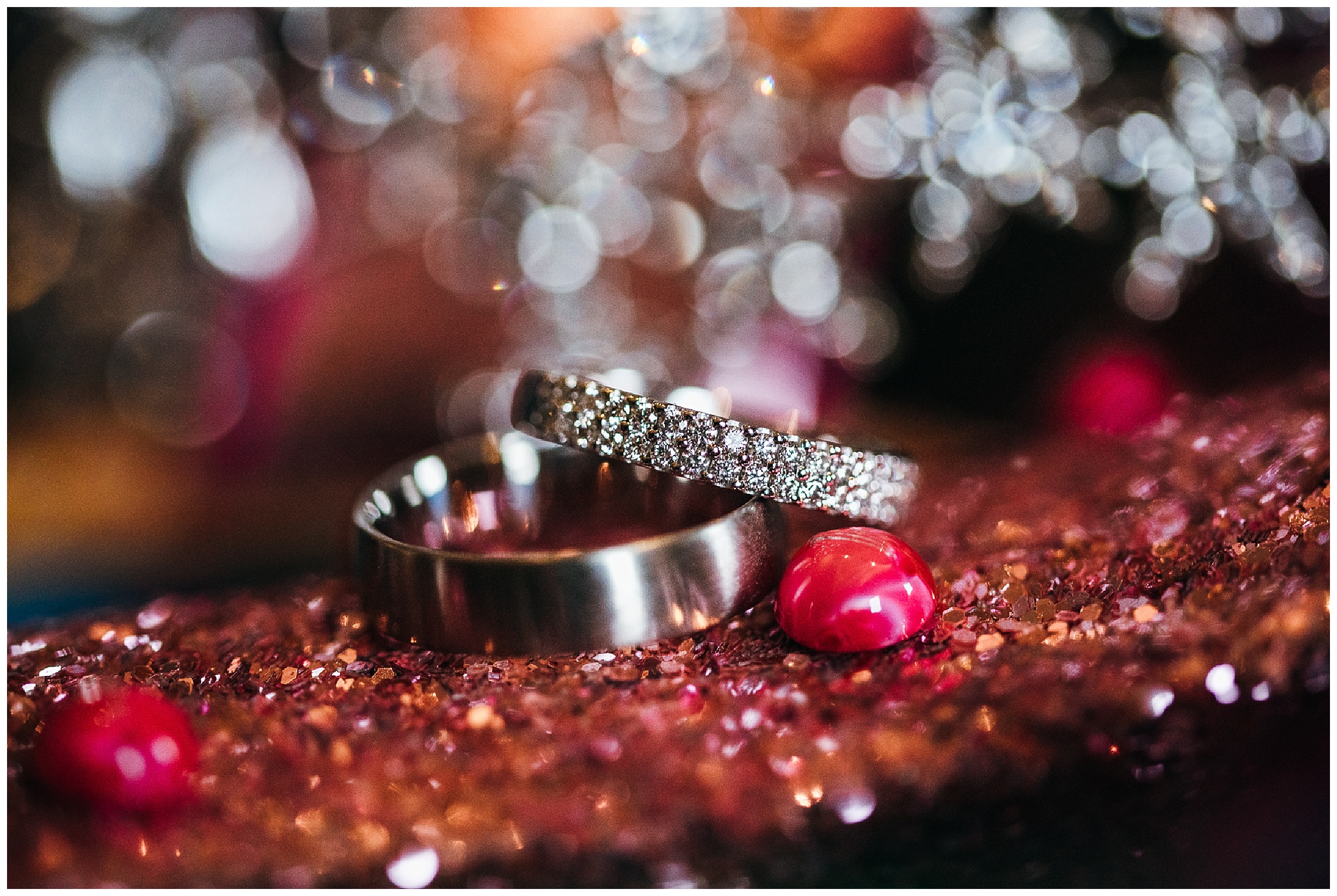 Silver wedding rings placed on pink glitter shoe with reflective background