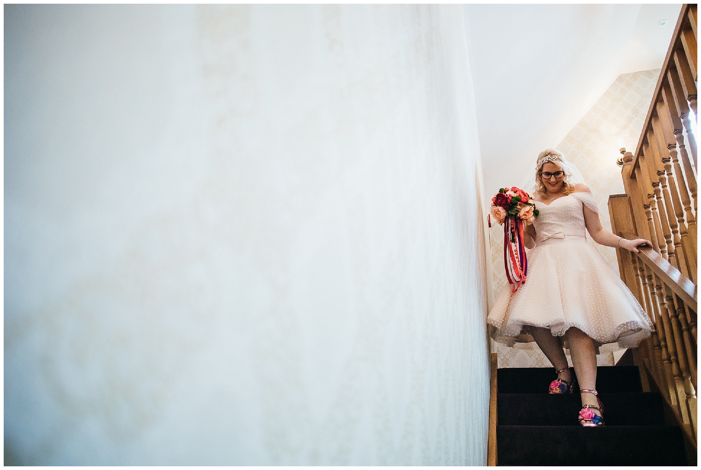 bride in short wedding dress and pink shoes descends stairs in bridal boudoir