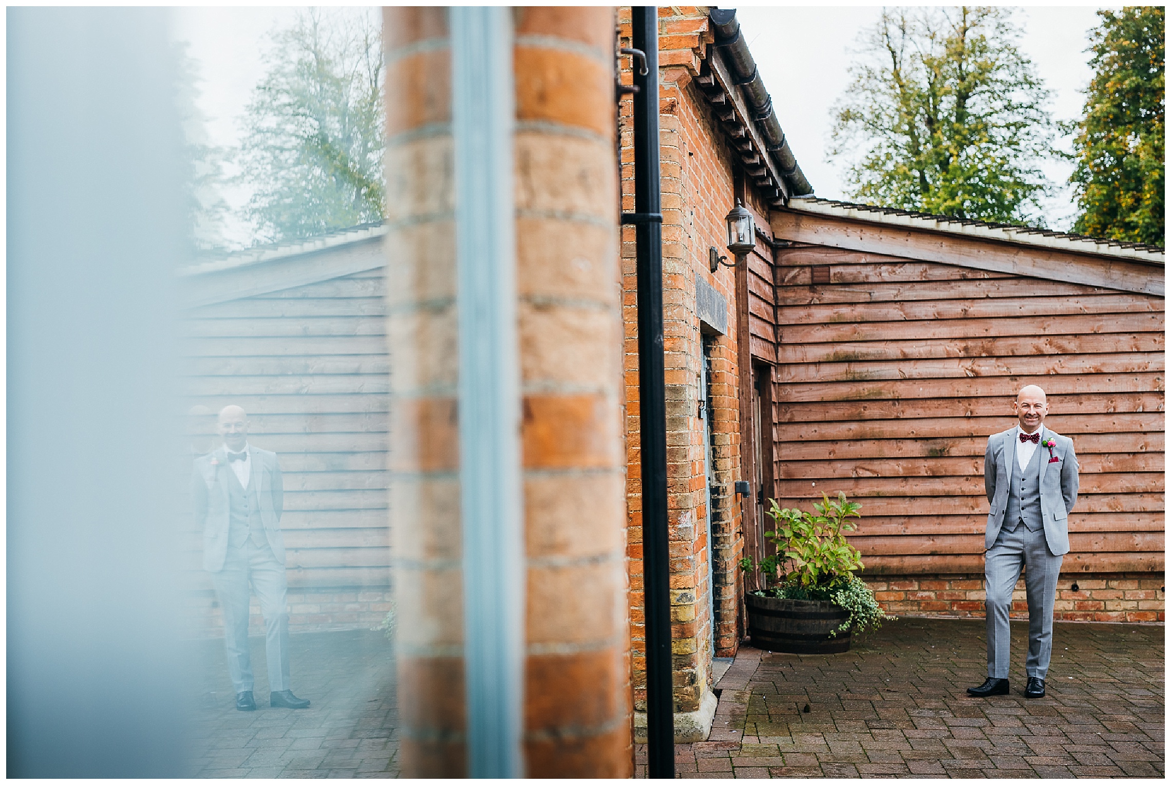 Father of the bride waits with his hands behind his back outside at bassmead manor