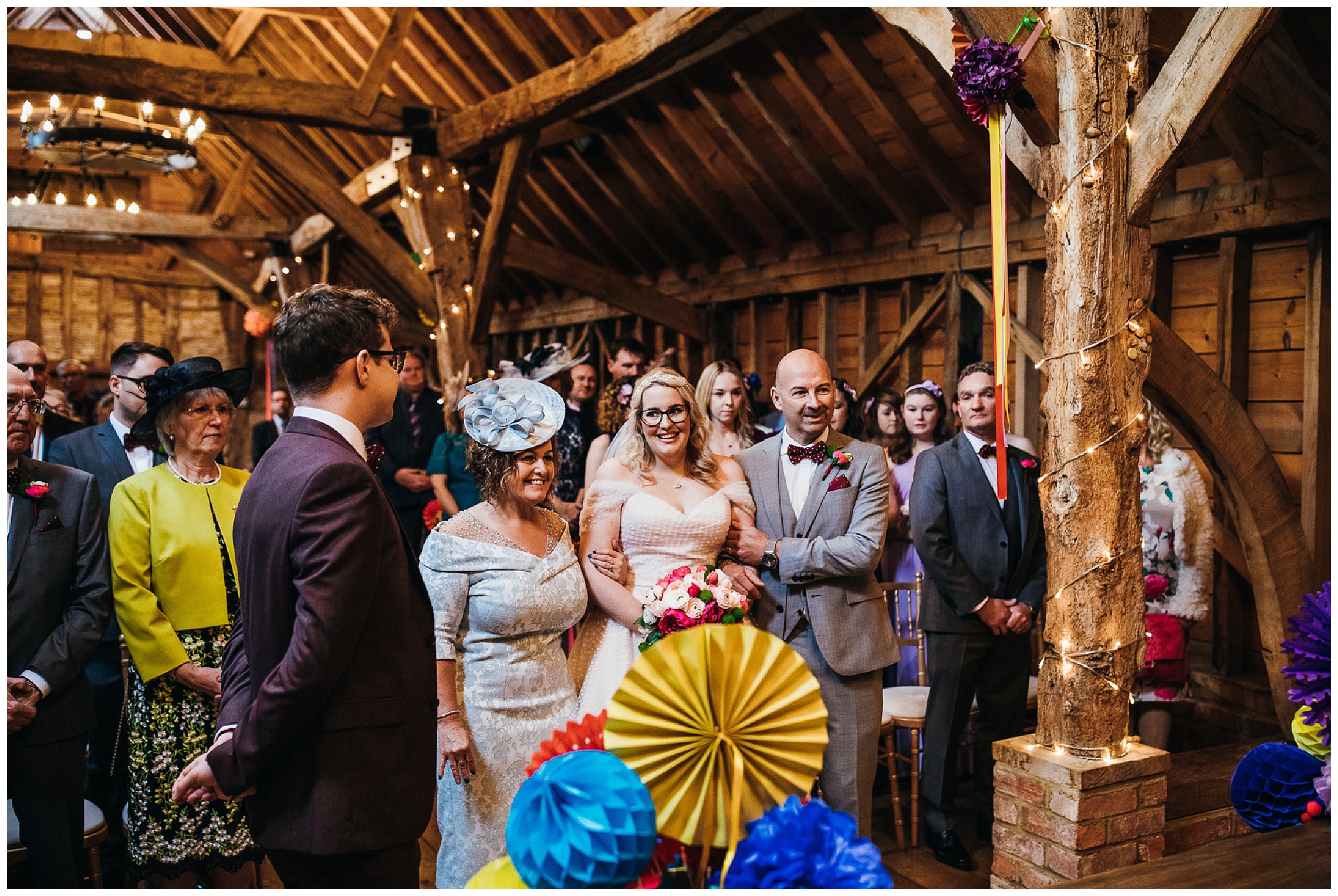 Bride and groom see each other for the first time and smile as father and mother walk bride down the aisle towards groom