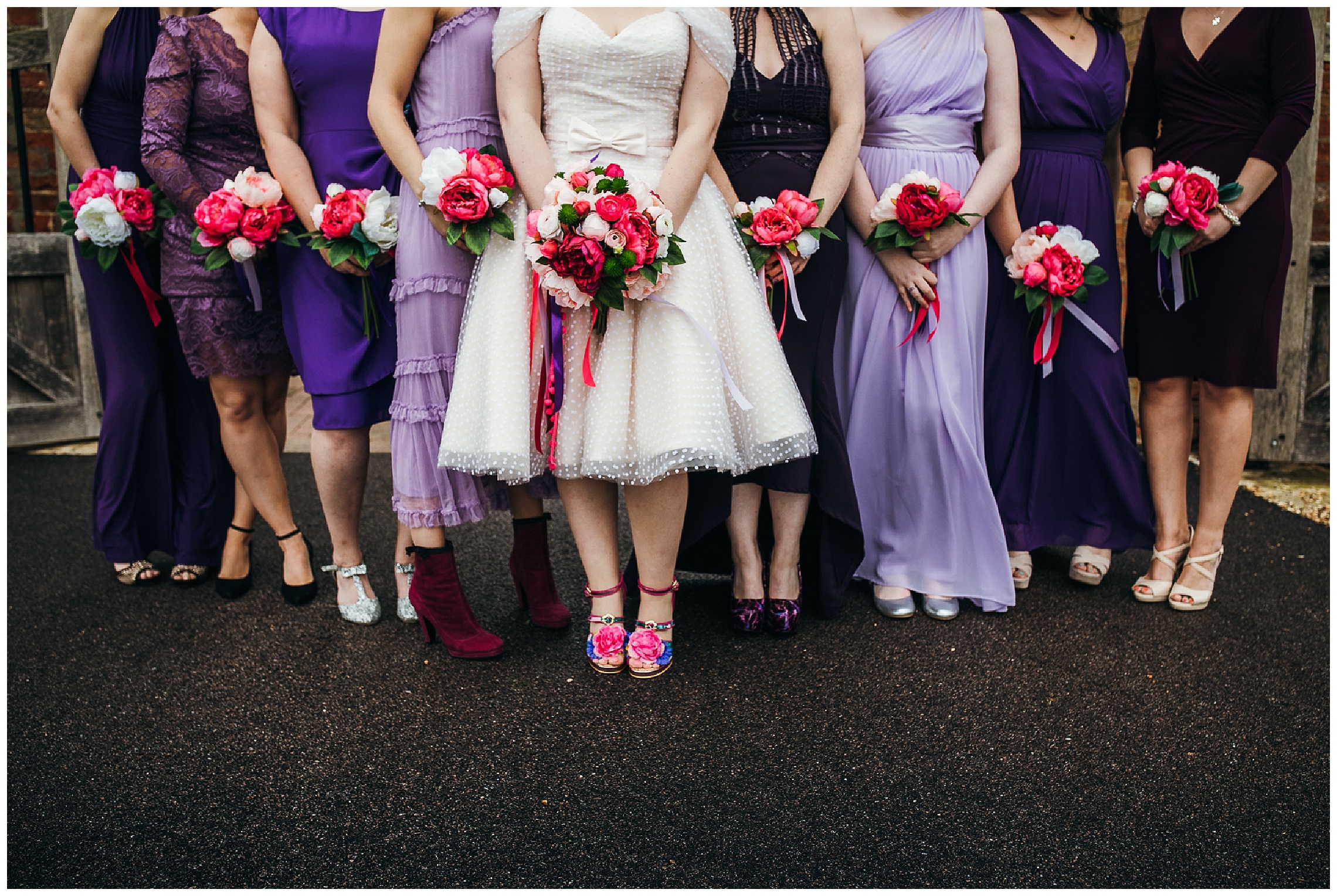 Bridesmaids in purple dresses clutching onto pink flowers