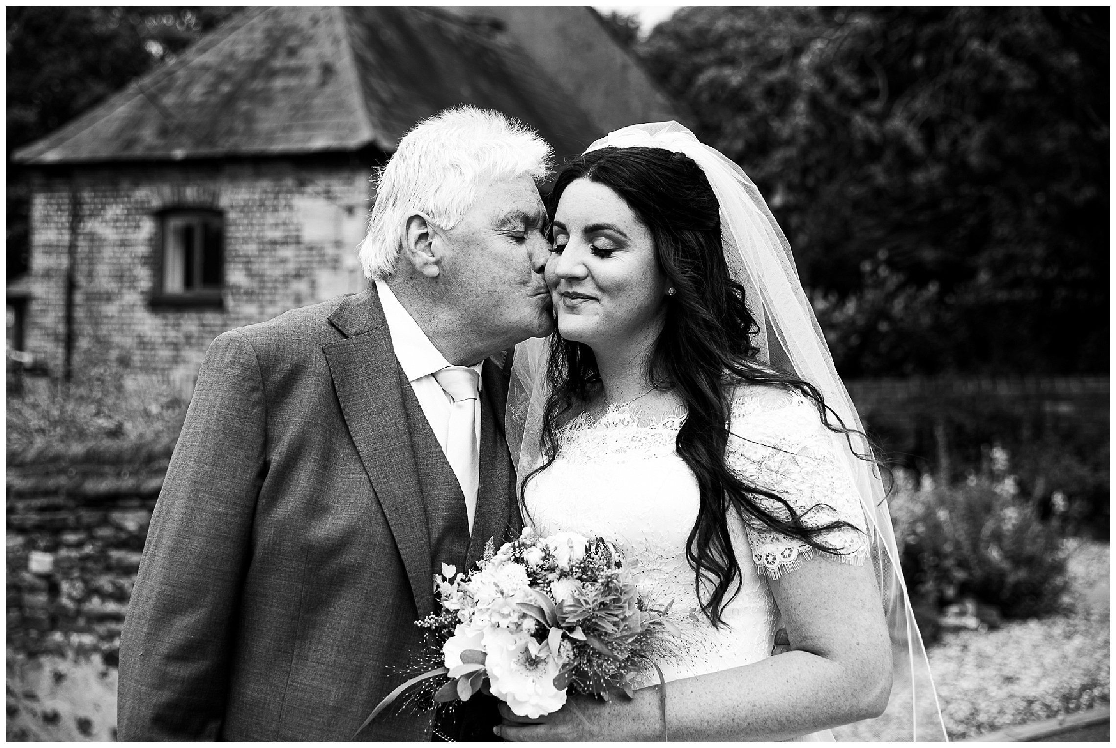 father of the bride kisses bride on the cheek before getting married