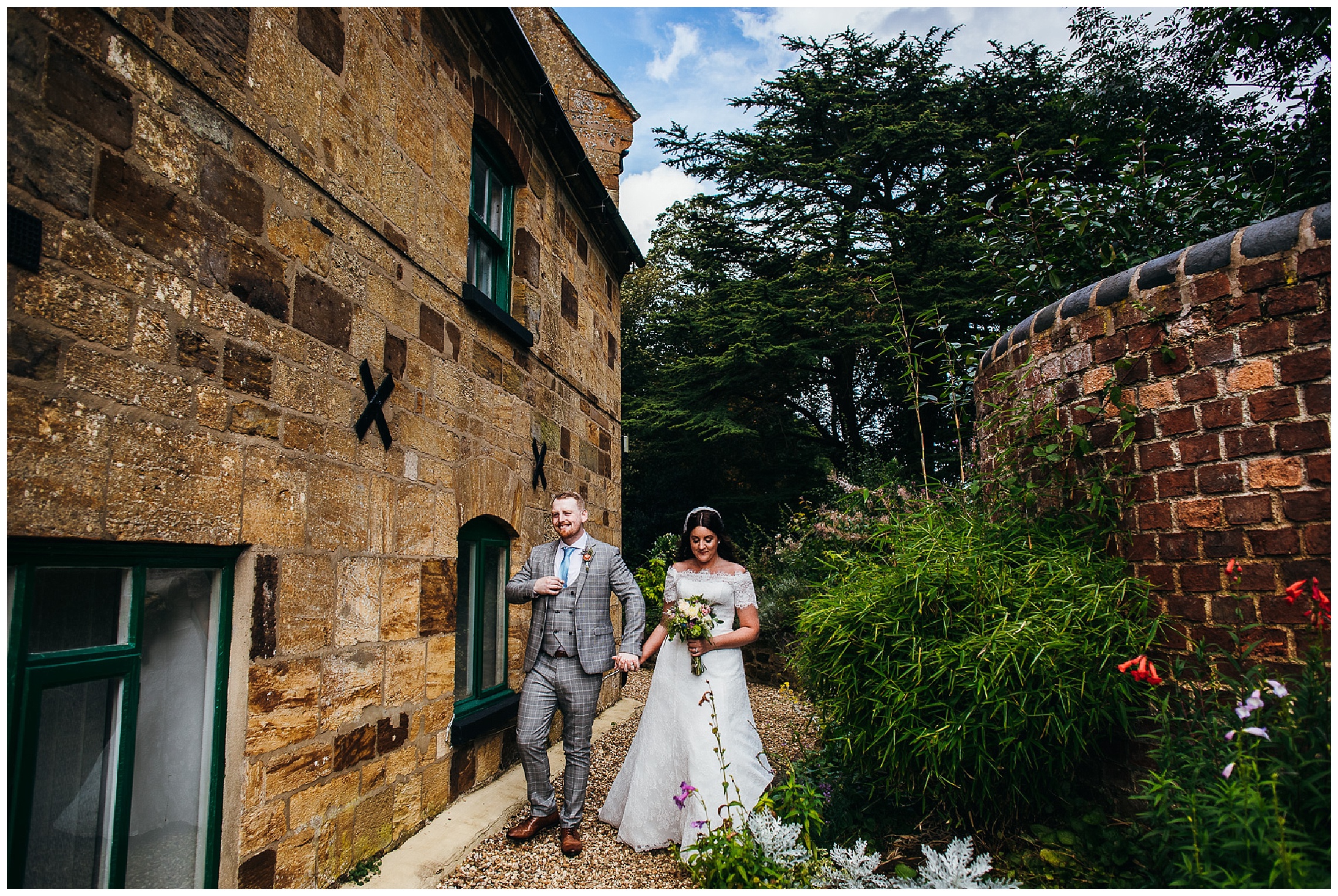 Bride and groom walk together through gardens hand in hand