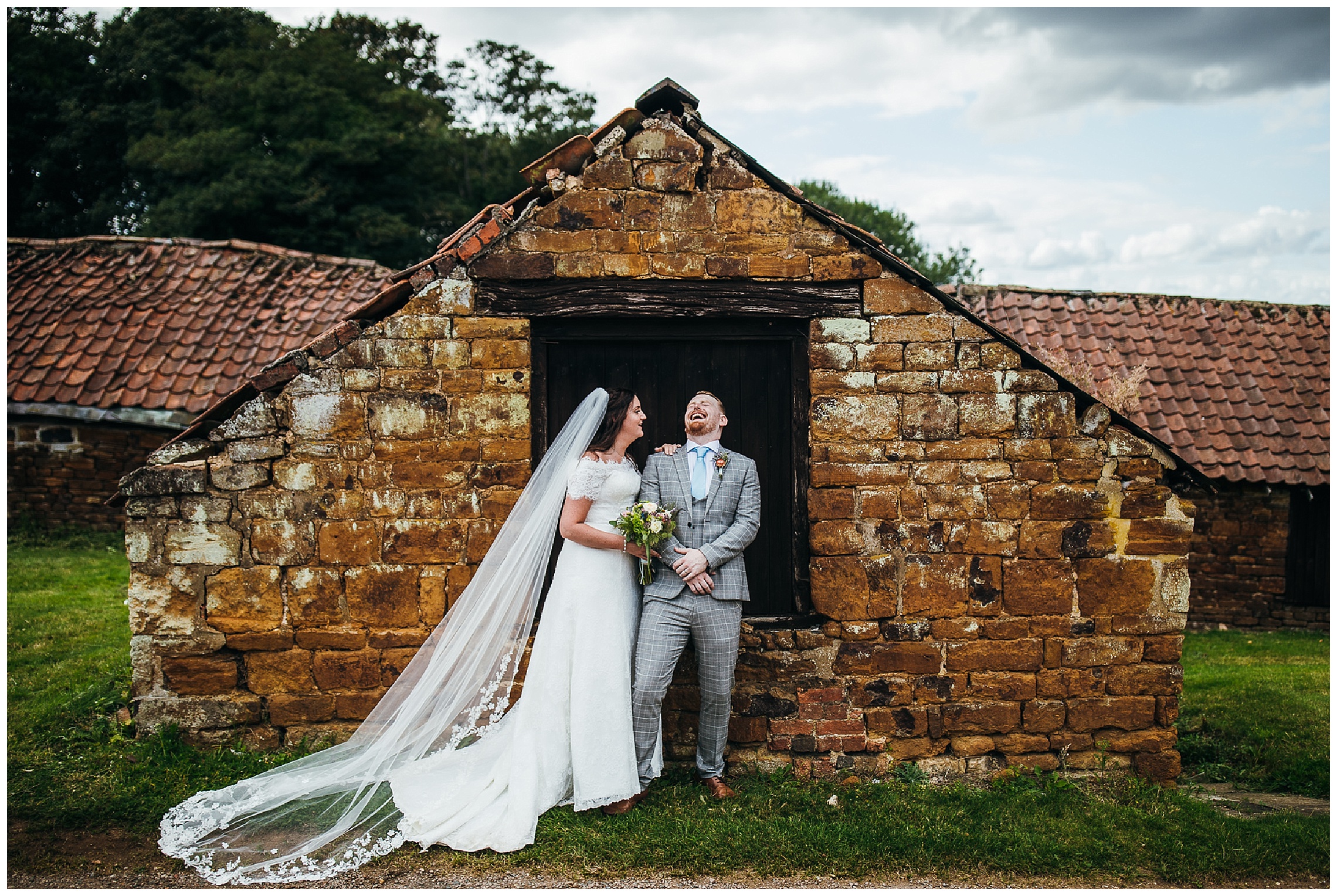 Bride and groom laughing in front of brick shed structure at hunsbury hill wedding venue