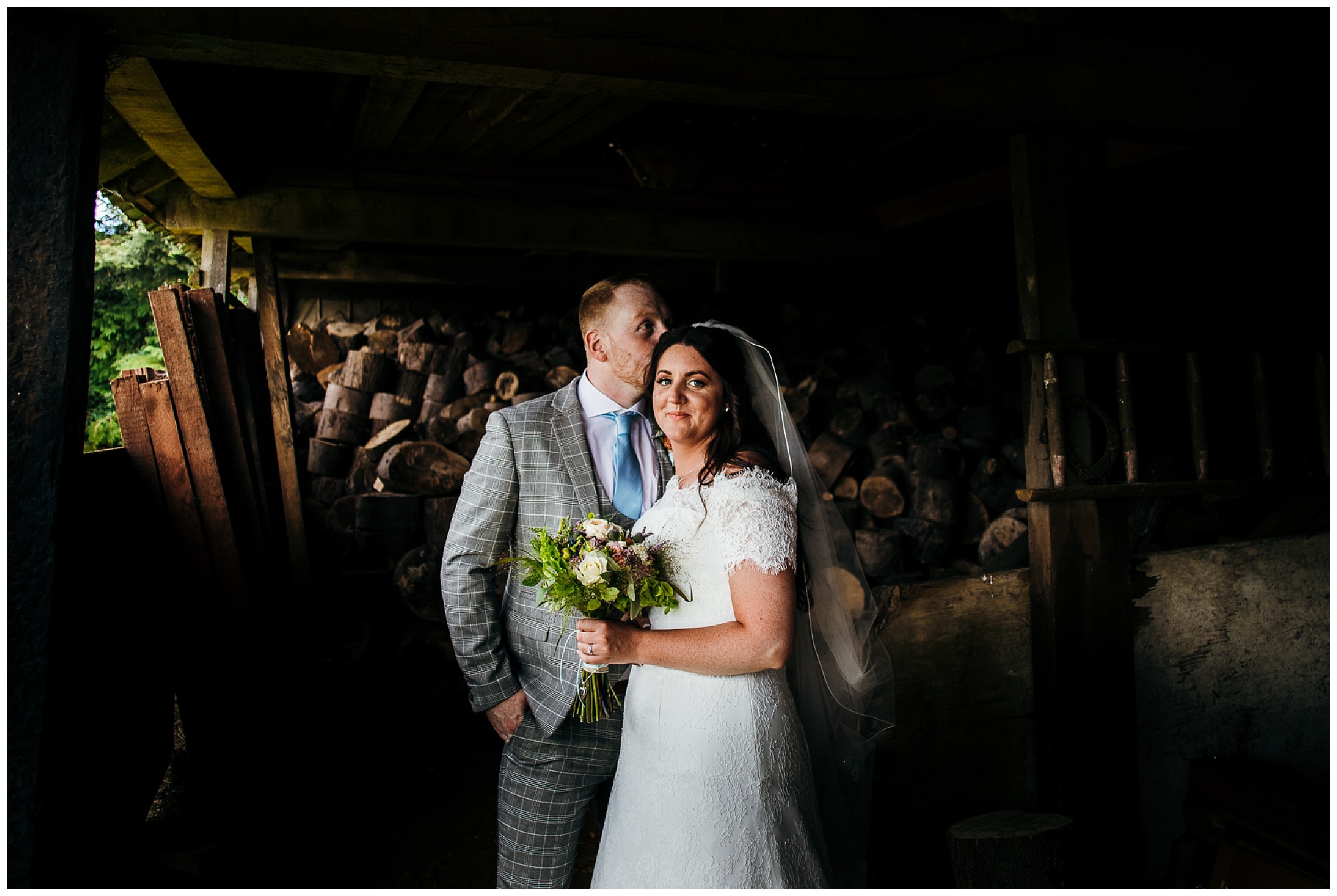 bride and groom standing together with flowers in dark shed