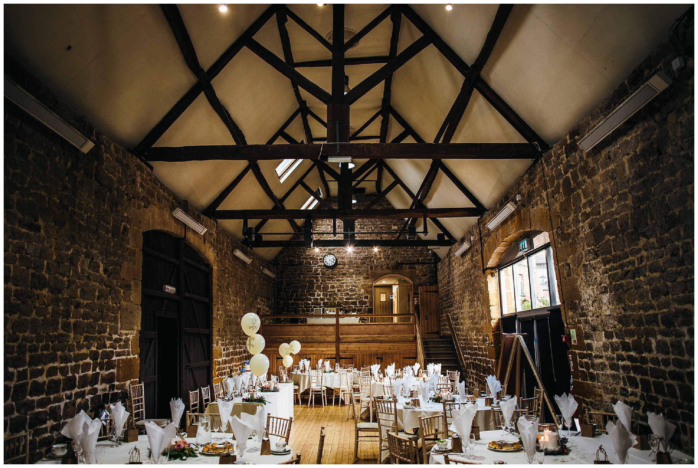 rustic wedding venue with wooden beams and brick walls, white tables and floral centrepieces