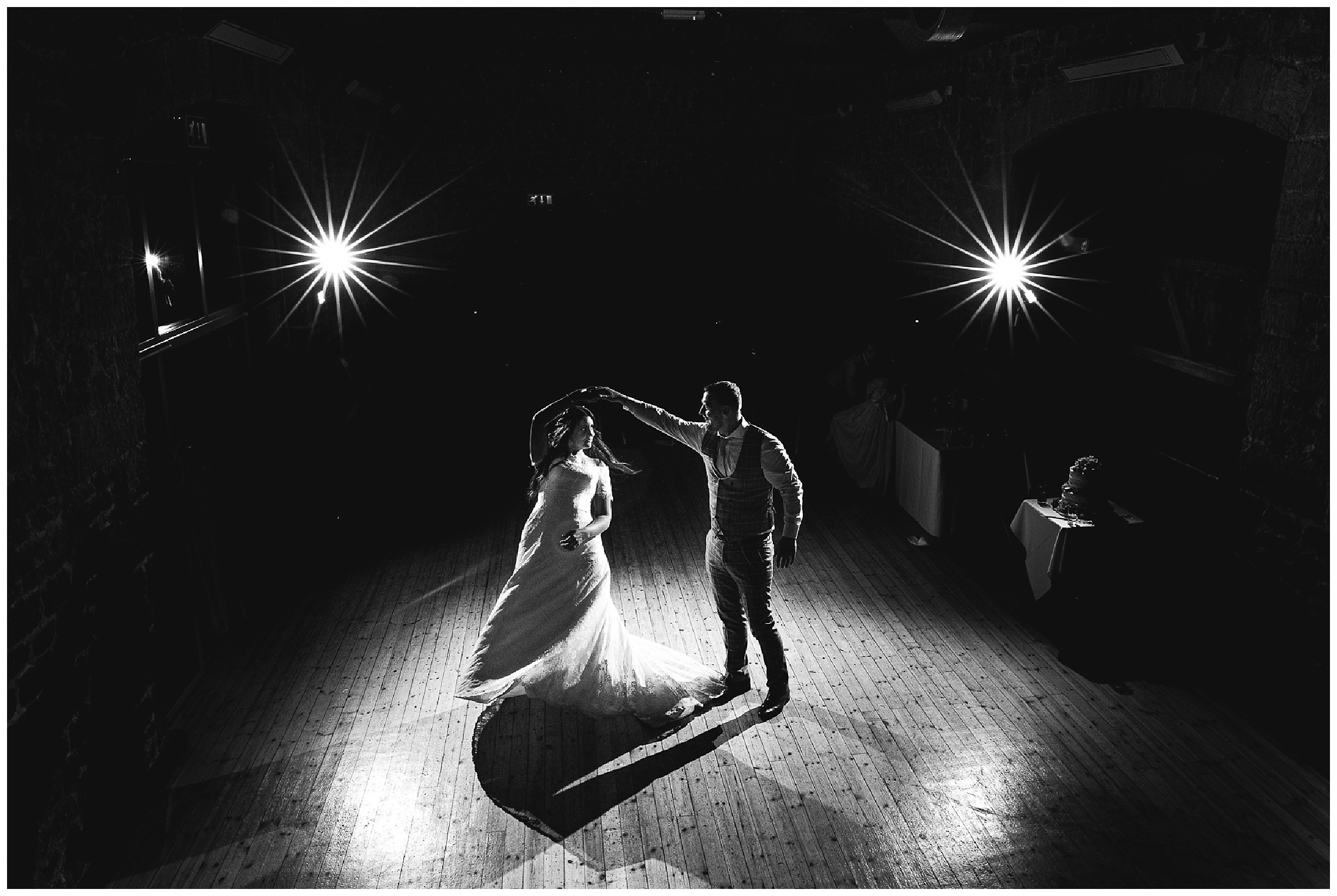 bride and groom dancing together in the dark illuminated by spotlights, at the barns at hunsbury hill brick barn wedding venue