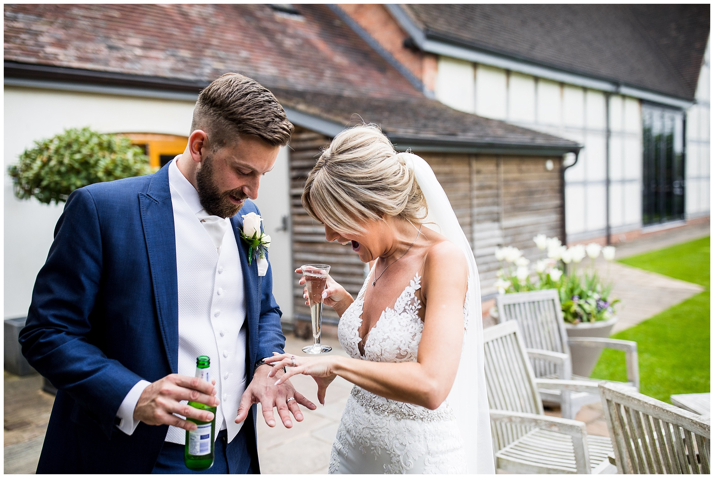 bride and groom outside barn venue looking at wedding rings on their fingers