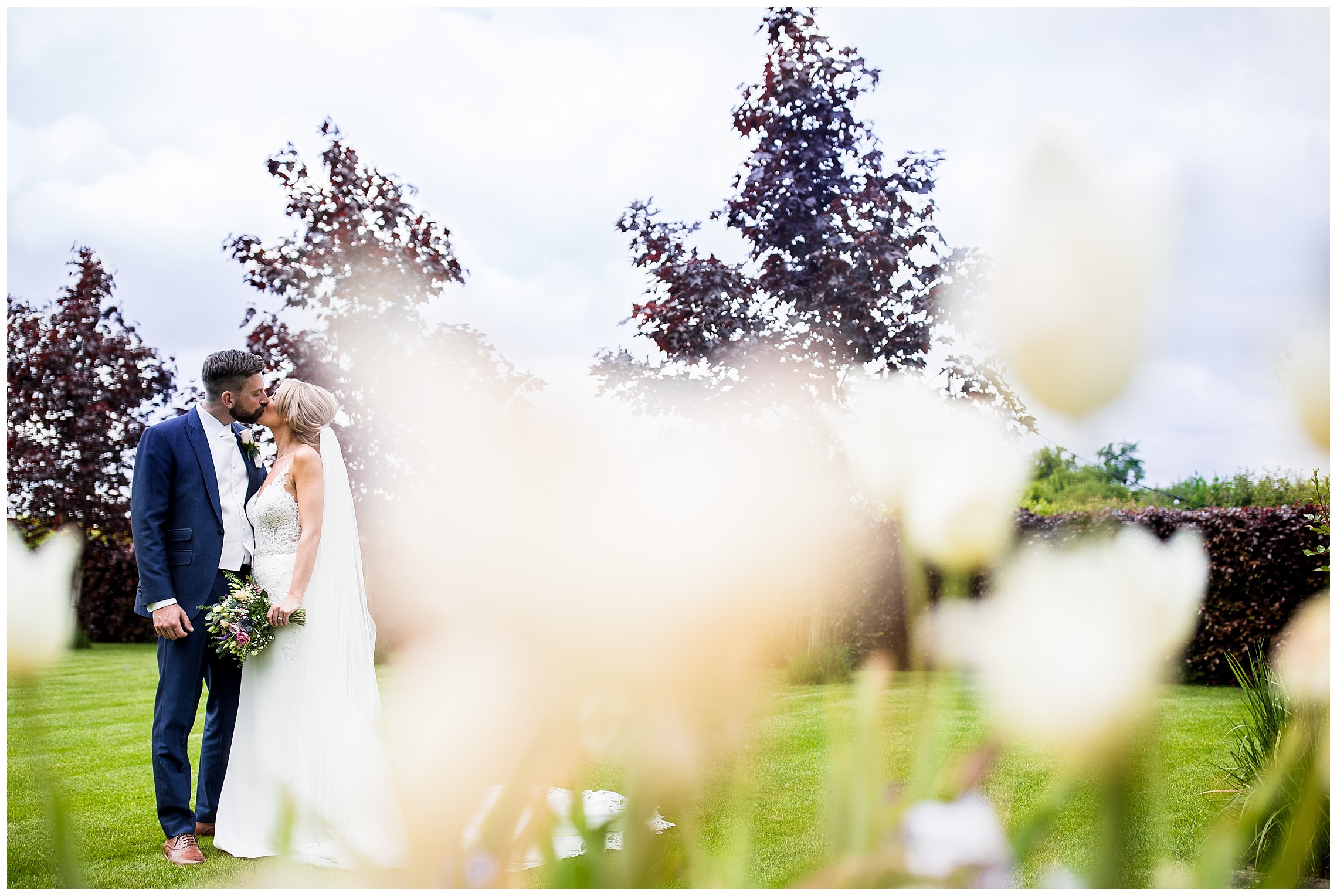 bride and groom kissing secretly behind plants