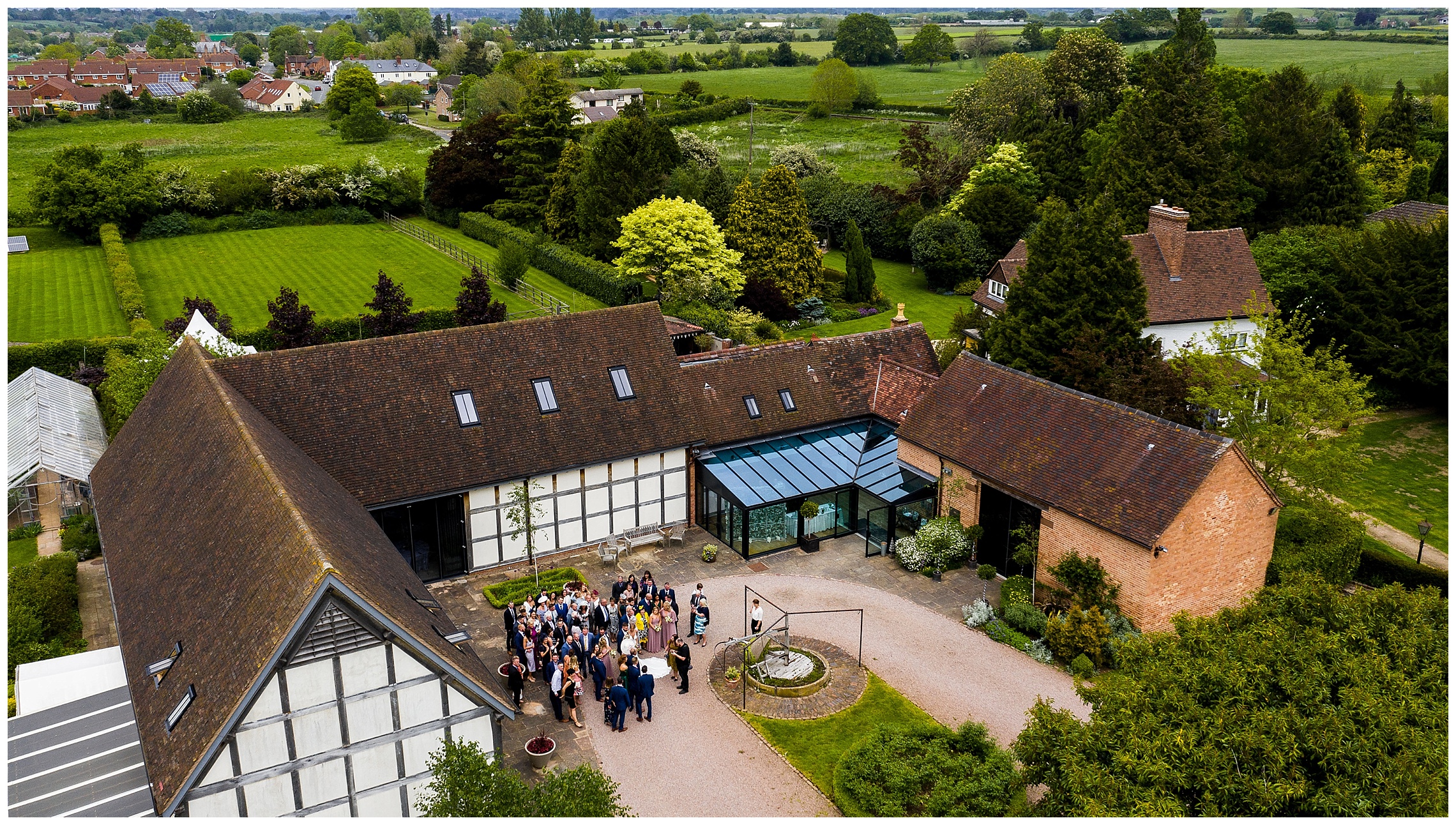 aerial shot of redhouse barn with wedding guests outside