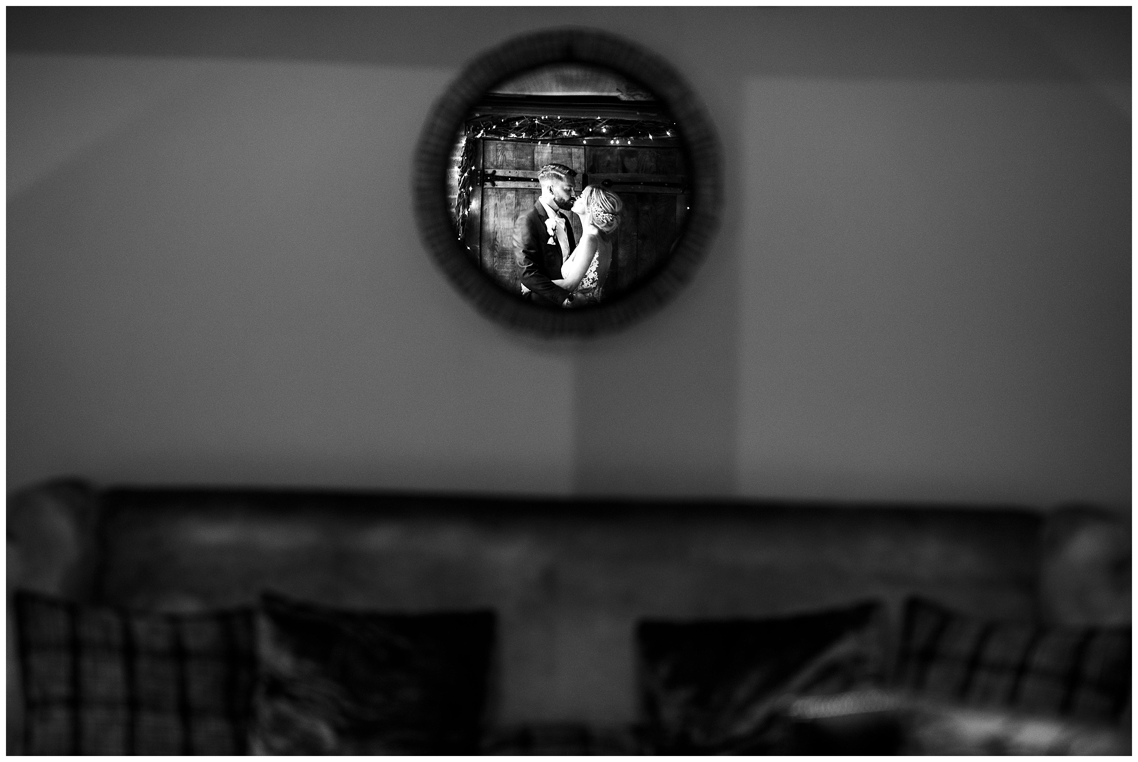 bride and groom kissing in reflection of small mirror in black and white