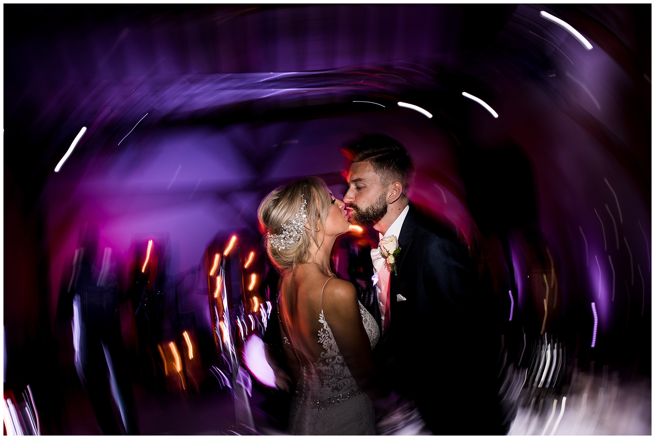 bride and groom kissing on dance floor with purple and pink lights