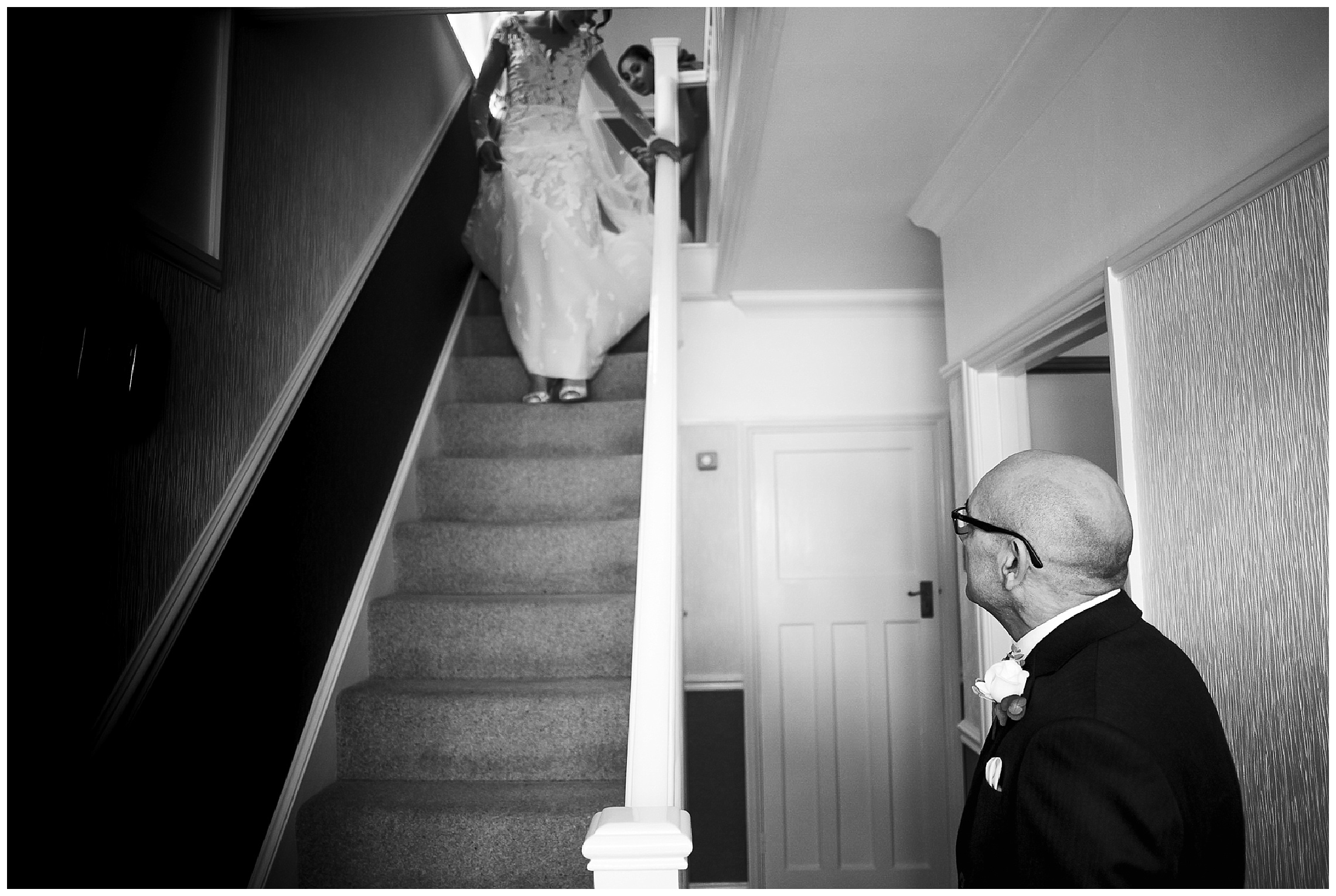 bride walks down stairs as father of the bride looks on