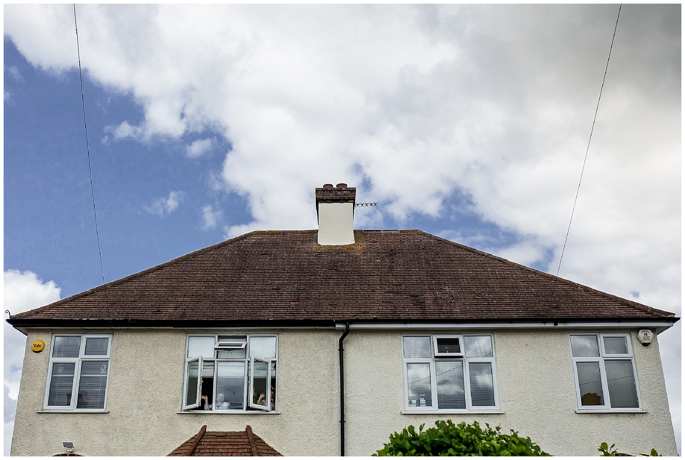 neighbours waving out of window in house opposite