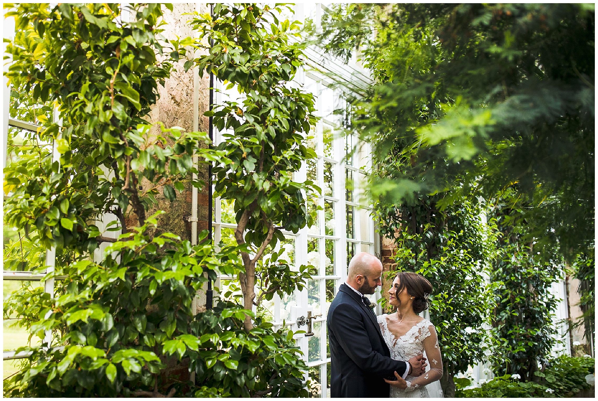 bride and groom surrounded by greenery in camellia house at woburn sculpture gallery
