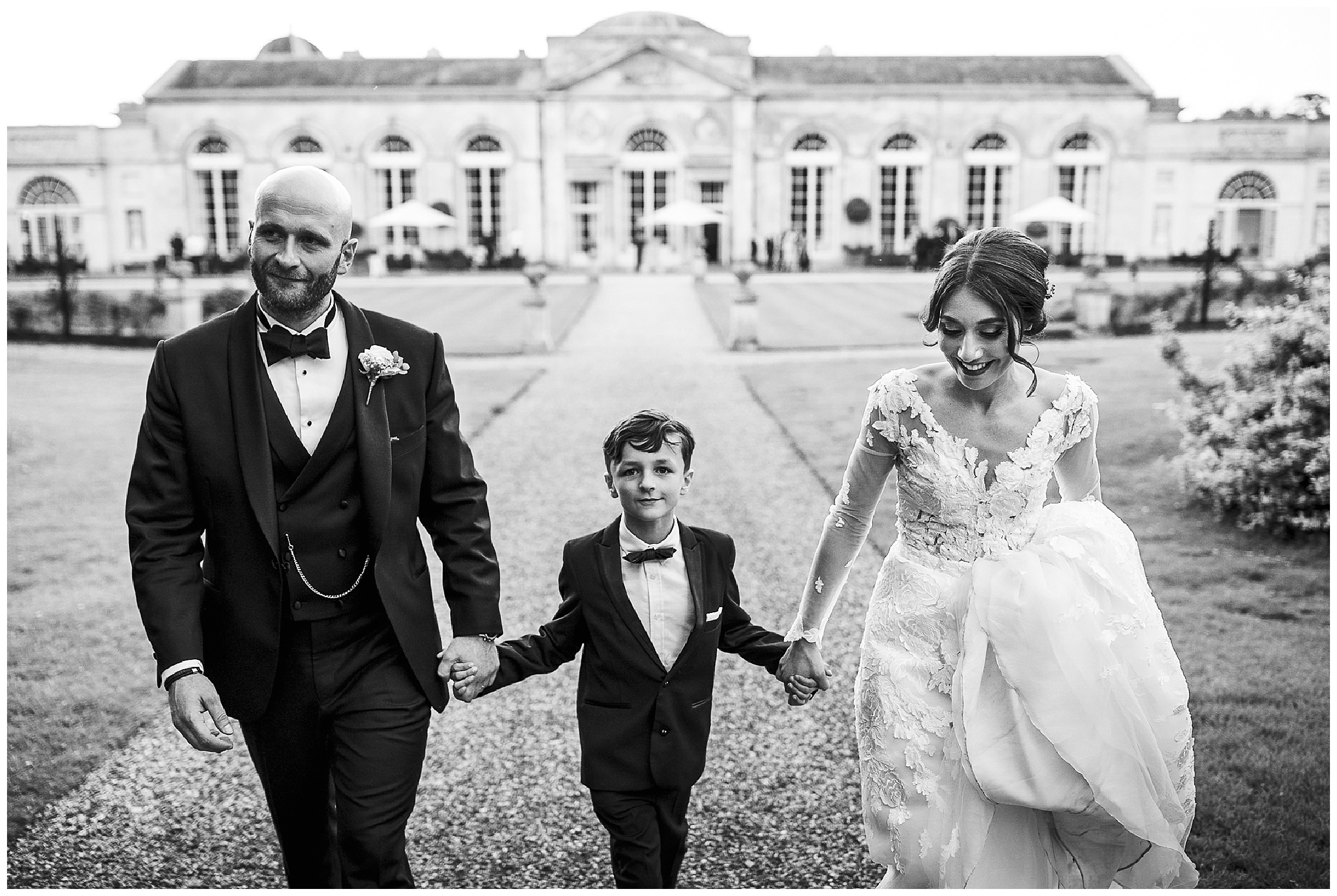 bride and groom walk hand in hand with son