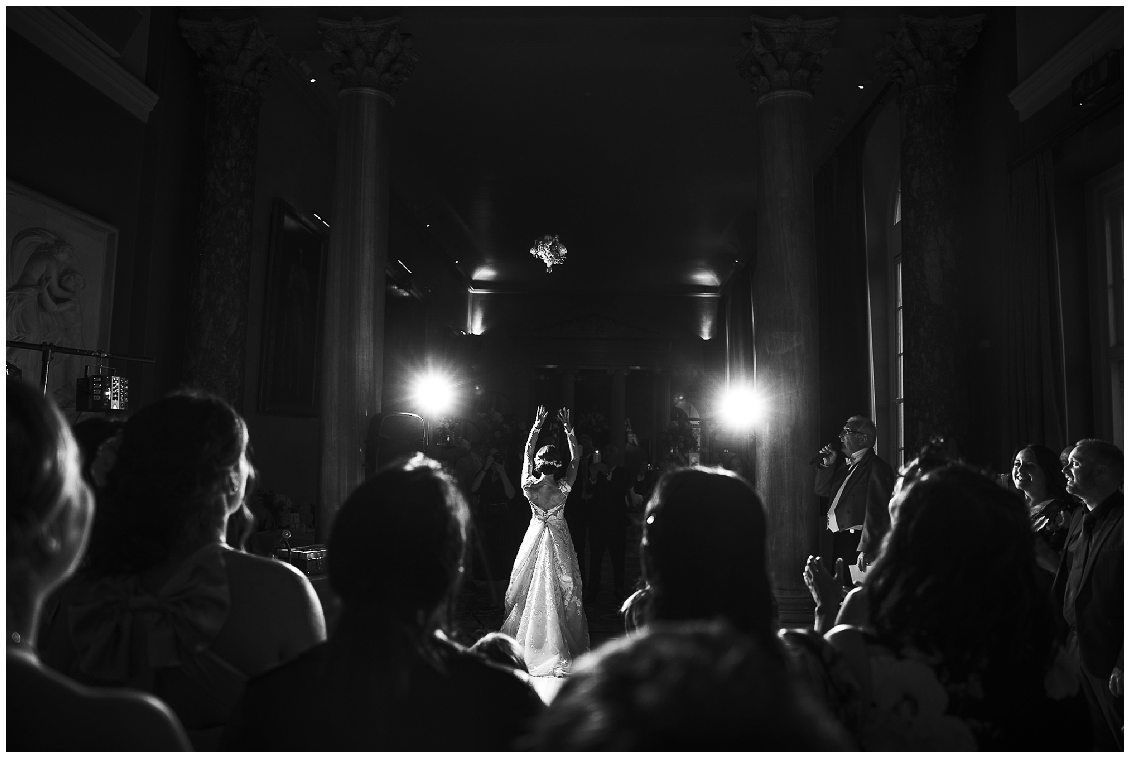 bride tosses bouquet over her head as girls look on with flowers in mid-air