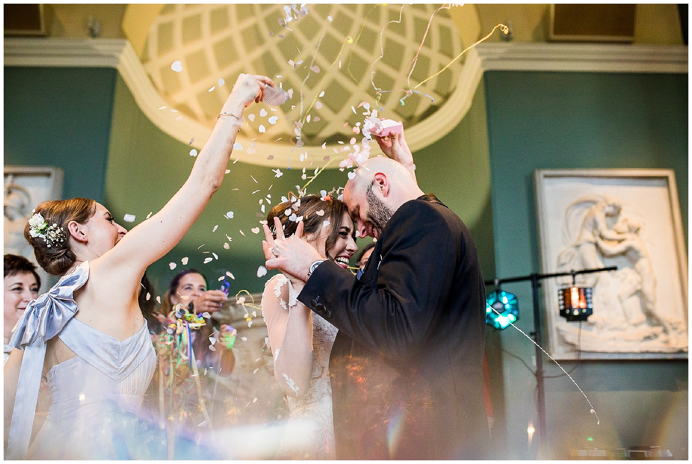 bride and groom dancing whilst wedding guests cover them in confetti and streamers