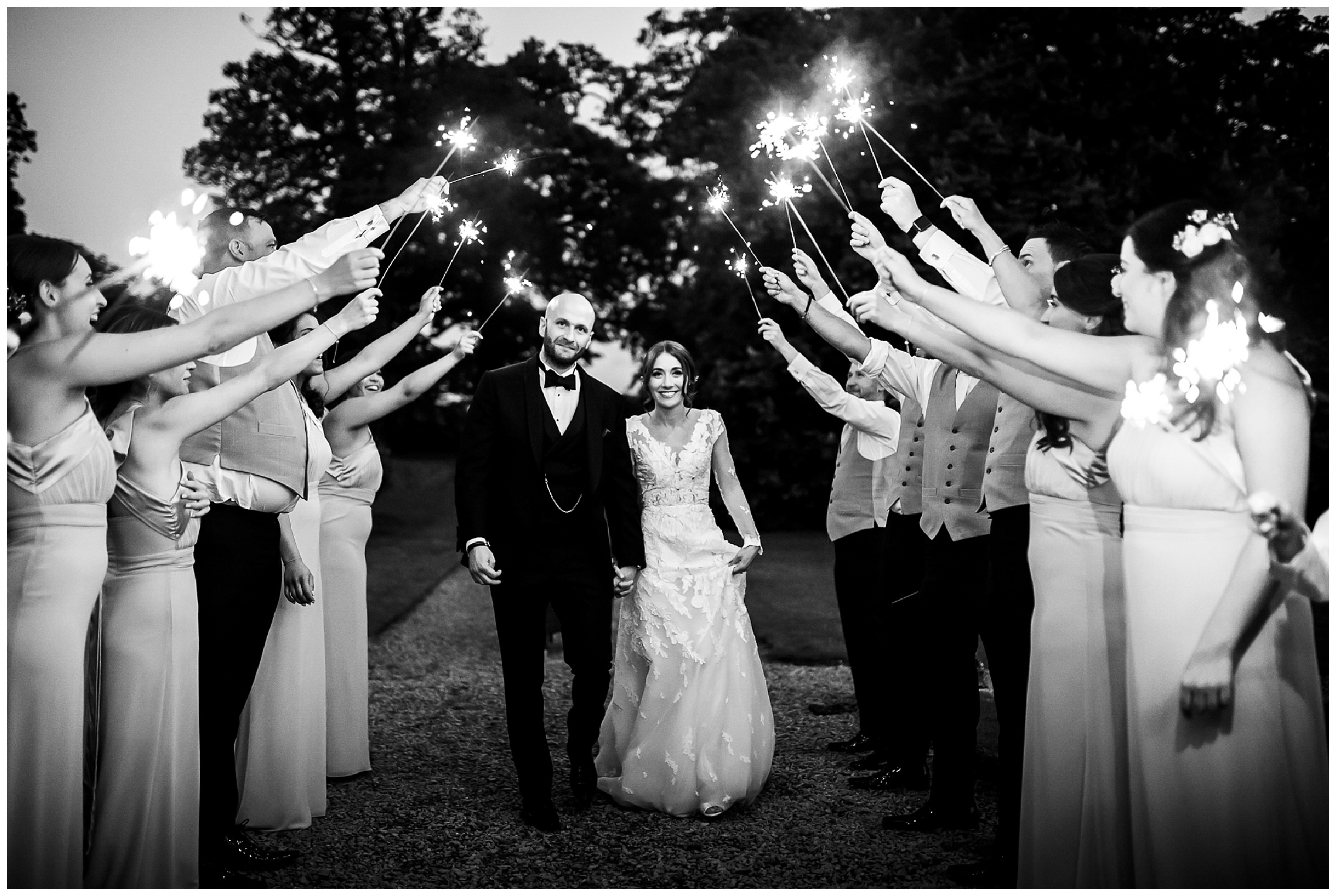 bride and groom holding hands and walking beneath tunnel of sparklers at woburn sculpture gallery