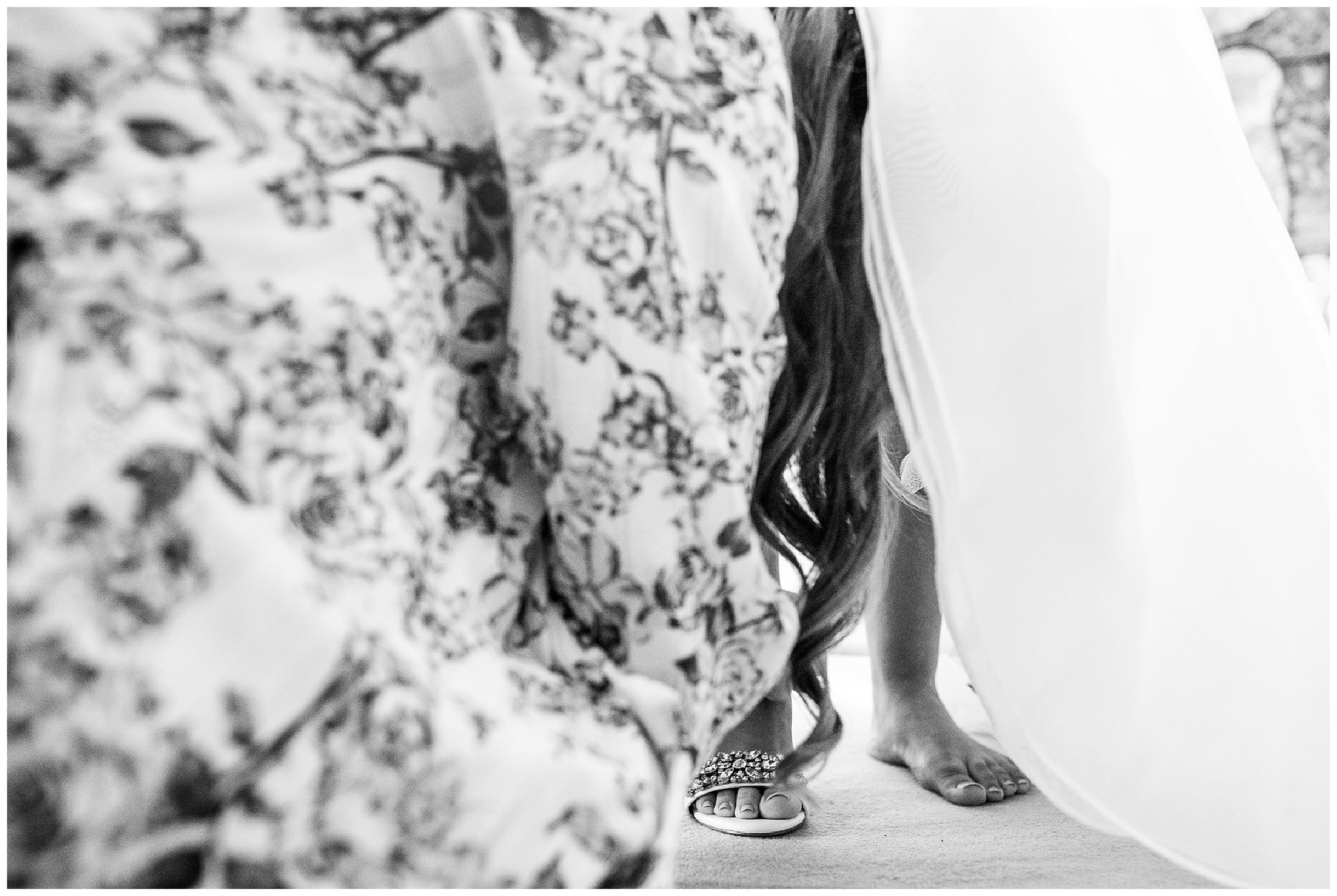 bride stepping into low heeled shoes with help of bridesmaid