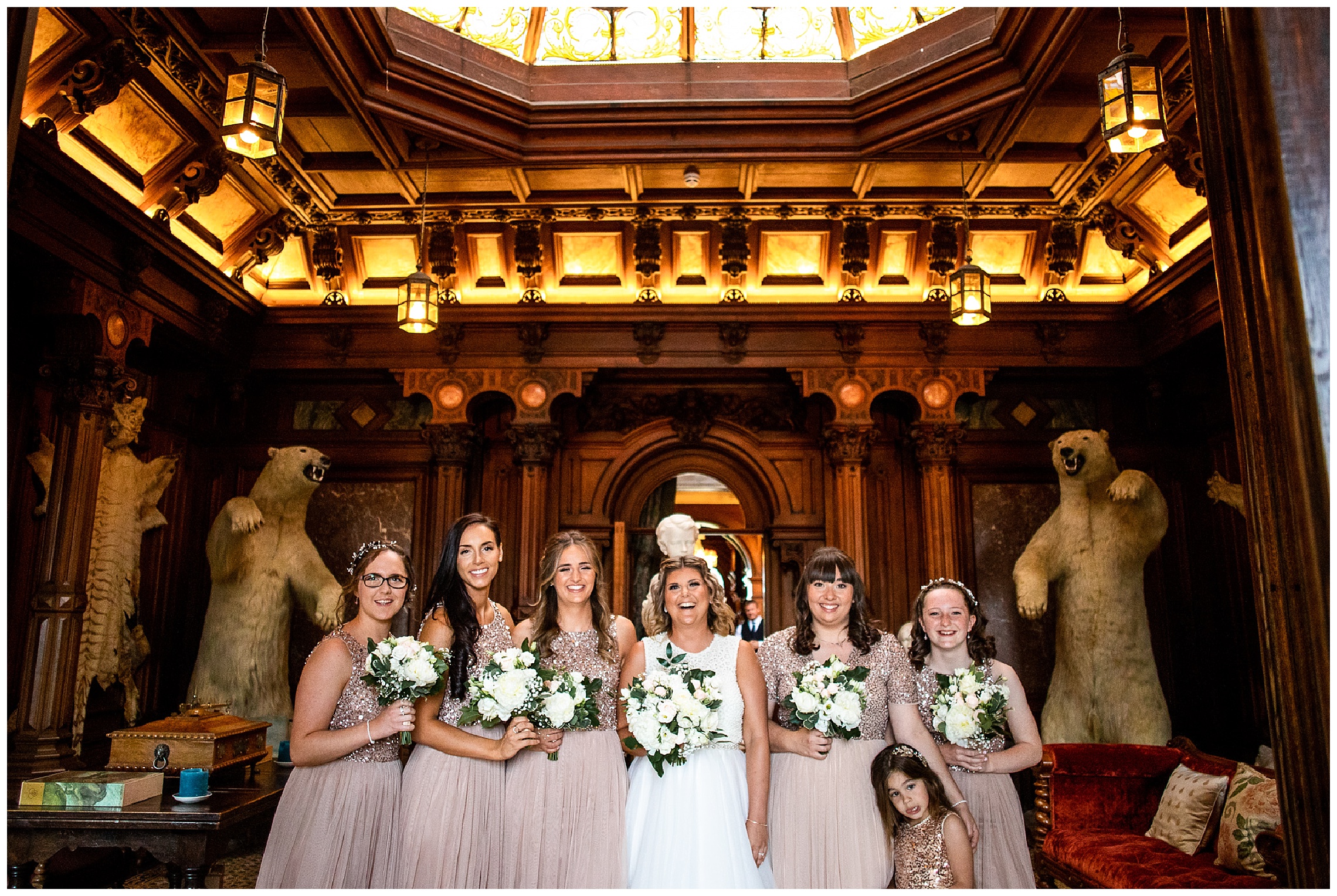 bride and bridesmaids with flowers standing in warm coloured lobby of somerleyton hall