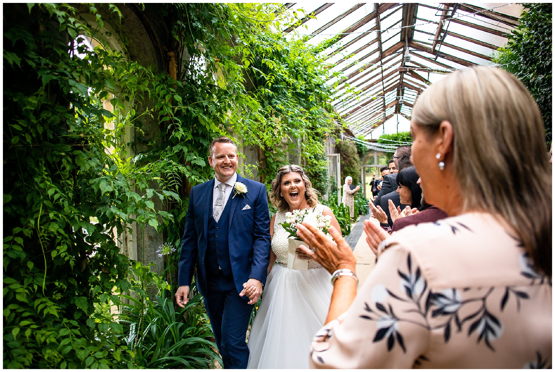 bride smiles at guests as her and groom leave the main ceremony room at somerleyton